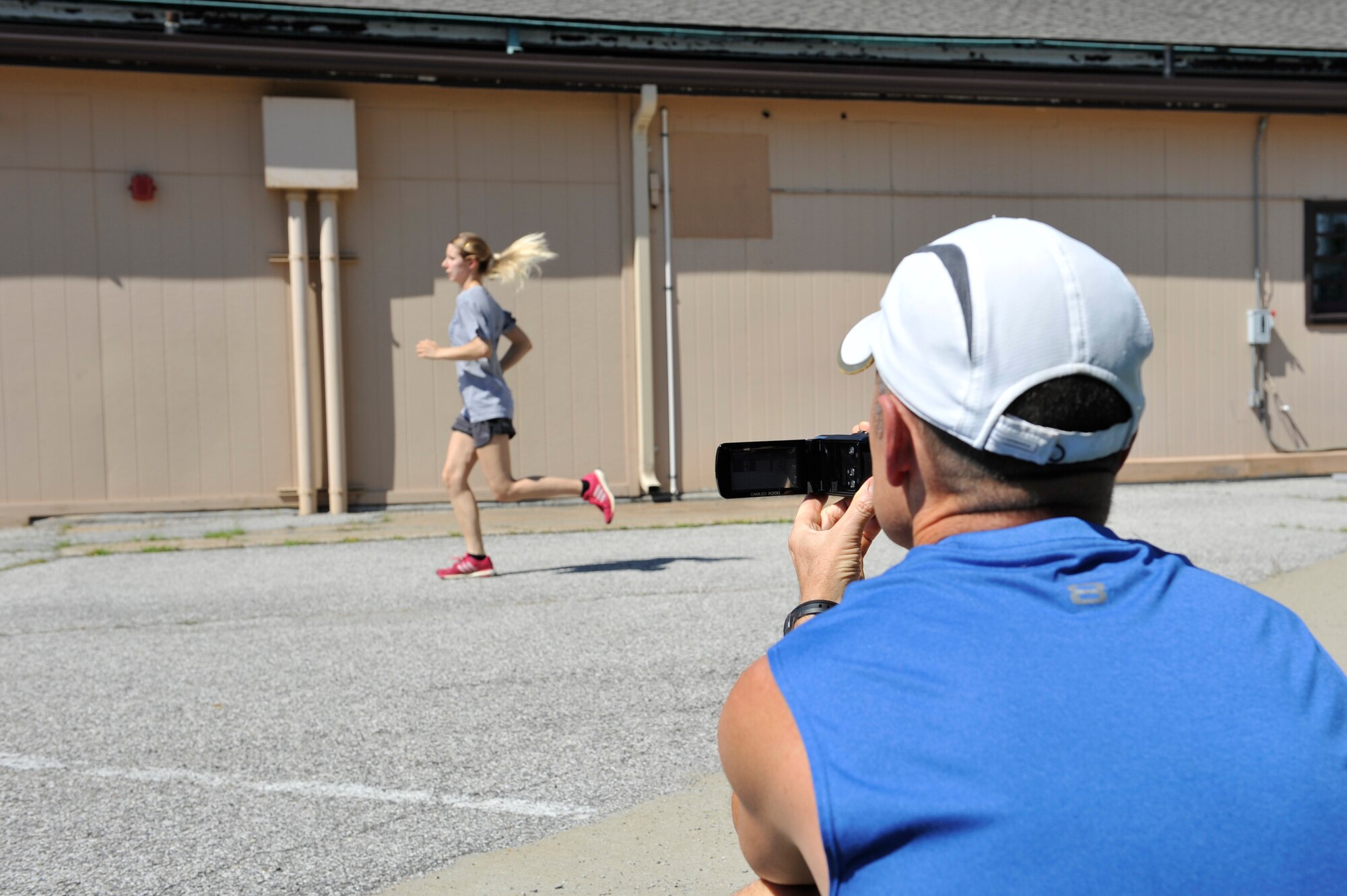 Al Bromley, 375th Aerospace Medicine Squadron Health Promotions Flight, records a member of Team Scott while they run during a pain free running clinic at Scott Air Force Base, Illinois on July 31, 2015. Bromley records their running so that he can help them analyze their running and correct their form, foot striking, and other aspects of running in order to make running easier. (U.S. Air Force photo by Senior Airman Sarah Hall-Kirchner/Released)