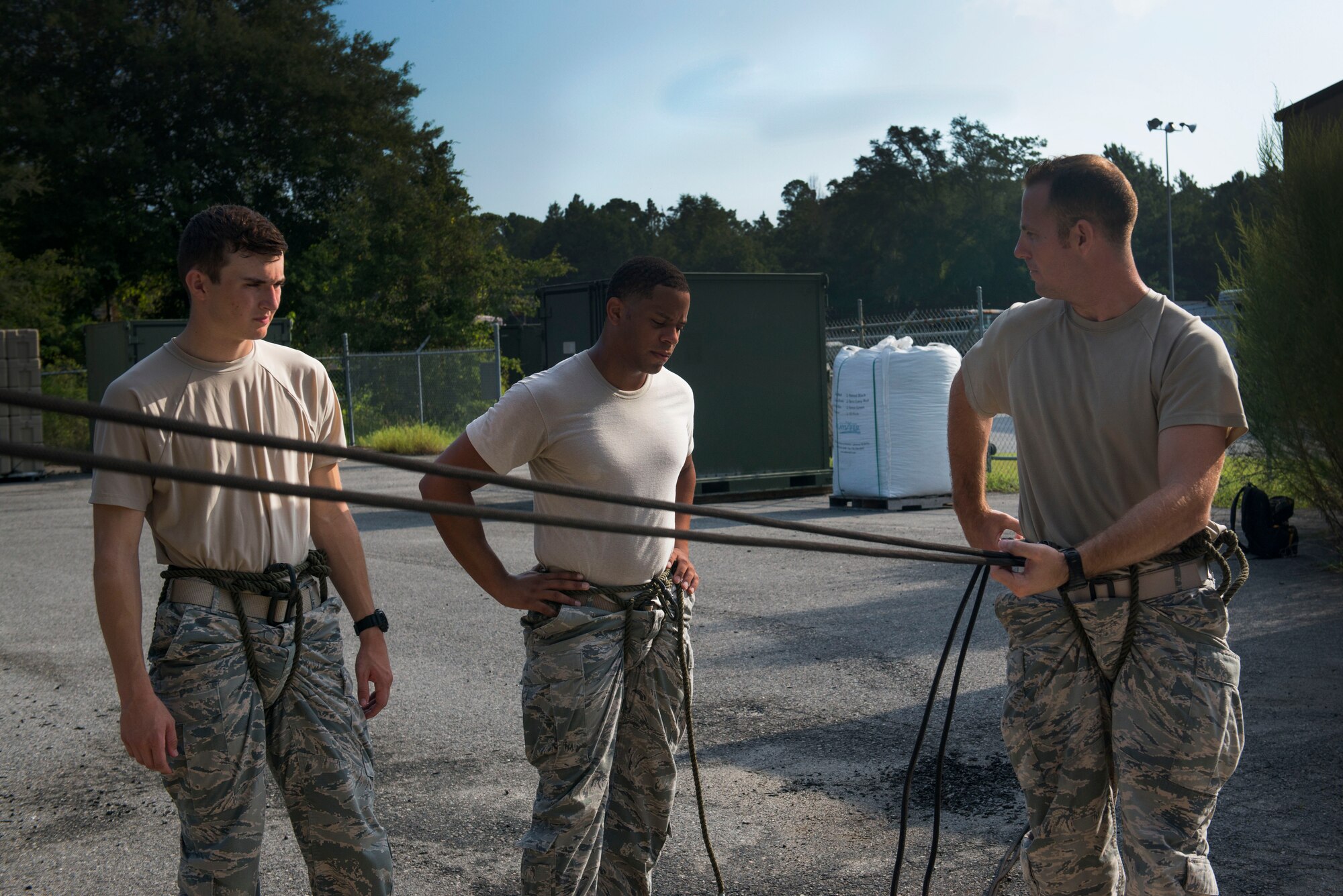 U.S. Air Force Staff Sgt. Michael Kearns (right), 820th Base Defense Group rappel master, demonstrates proper rappel form to Airman 1st Class Jeffrey Lewis (left), 822d Base Defense Squadron fire team member, and Staff Sgt. Daniel Centreras, 822d BDS fire team leader, during a rappel training session Aug. 5, 2015, at Moody Air Force Base, Ga. Kearns warned the defenders on how improper hand grip could lead to injuries. (U.S. Air Force photo by Airman 1st Class Dillian Bamman/Released)