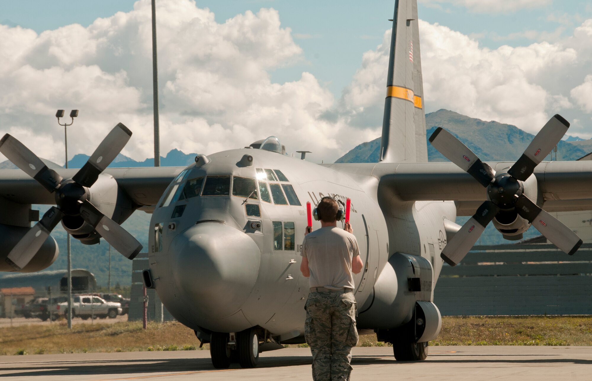 A member of the 176th Maintenance Group marshals in a C-130 Hercules aircraft on Joint Base Elmendorf-Richardson, Alaska, Aug. 11, 2015, returning from its morning mission. Alaska Air Guardsmen of the 176th Wing train alongside their international counterparts as part of Red Flag-Alaska 15-3. (Alaska Air National Guard photo by Tech. Sgt N. Alicia Halla/released)
