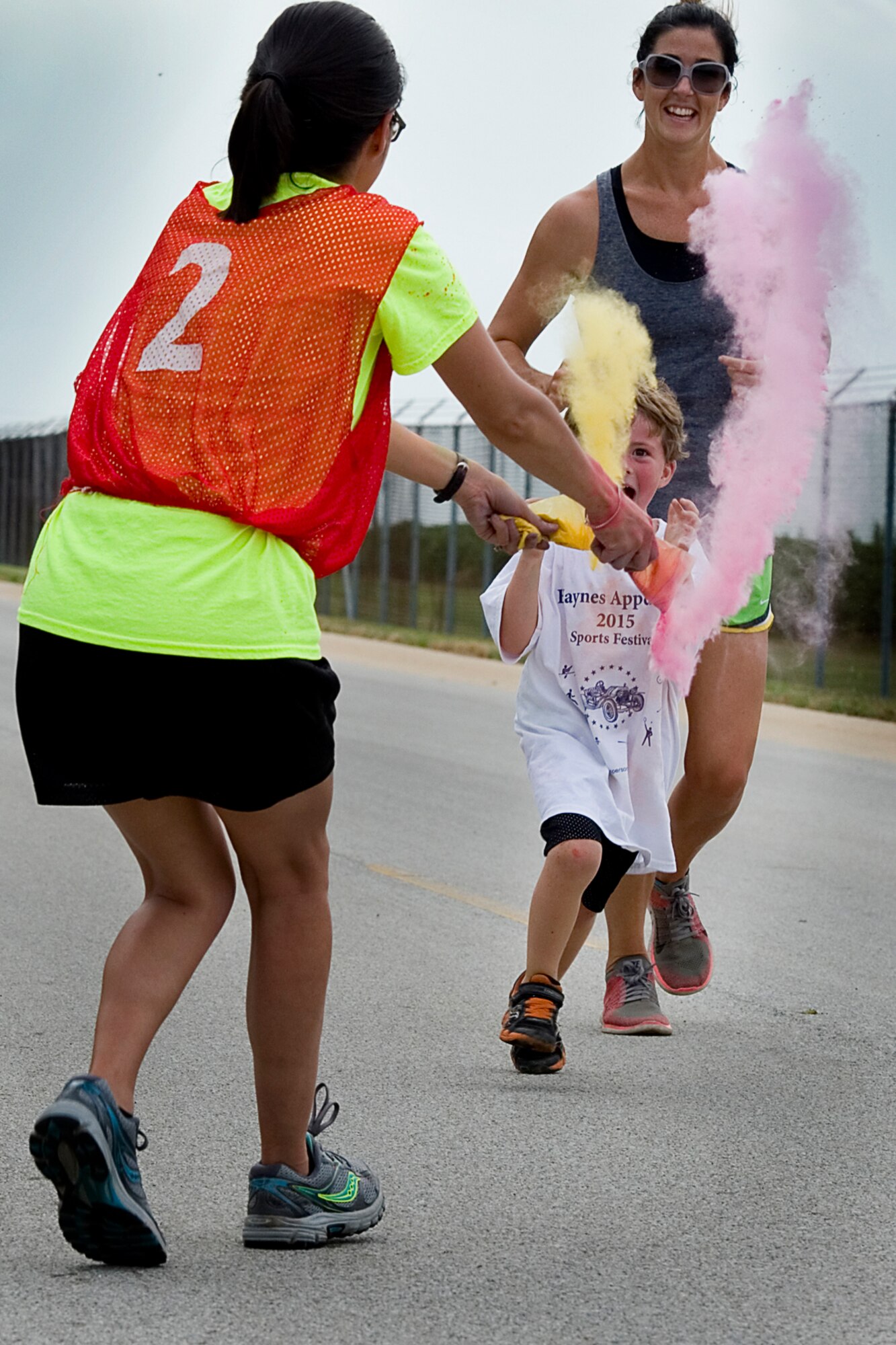 Paxton Strader and his mom Kellie Strader, family of Tech. Sgt. Timothy Strader, 434th Civil Engineer Squadron noncommissioned officer in charge of equipment, run the gauntlet against a volunteer during a 5k color fun run held August 8, 2015 at Grissom Air Reserve Base, Ind. Eighteen runners faced high temperatures and volunteers set on dousing them with bright colored powder. (U.S. Air Force photo/Senior Airman Jami K. Lancette)