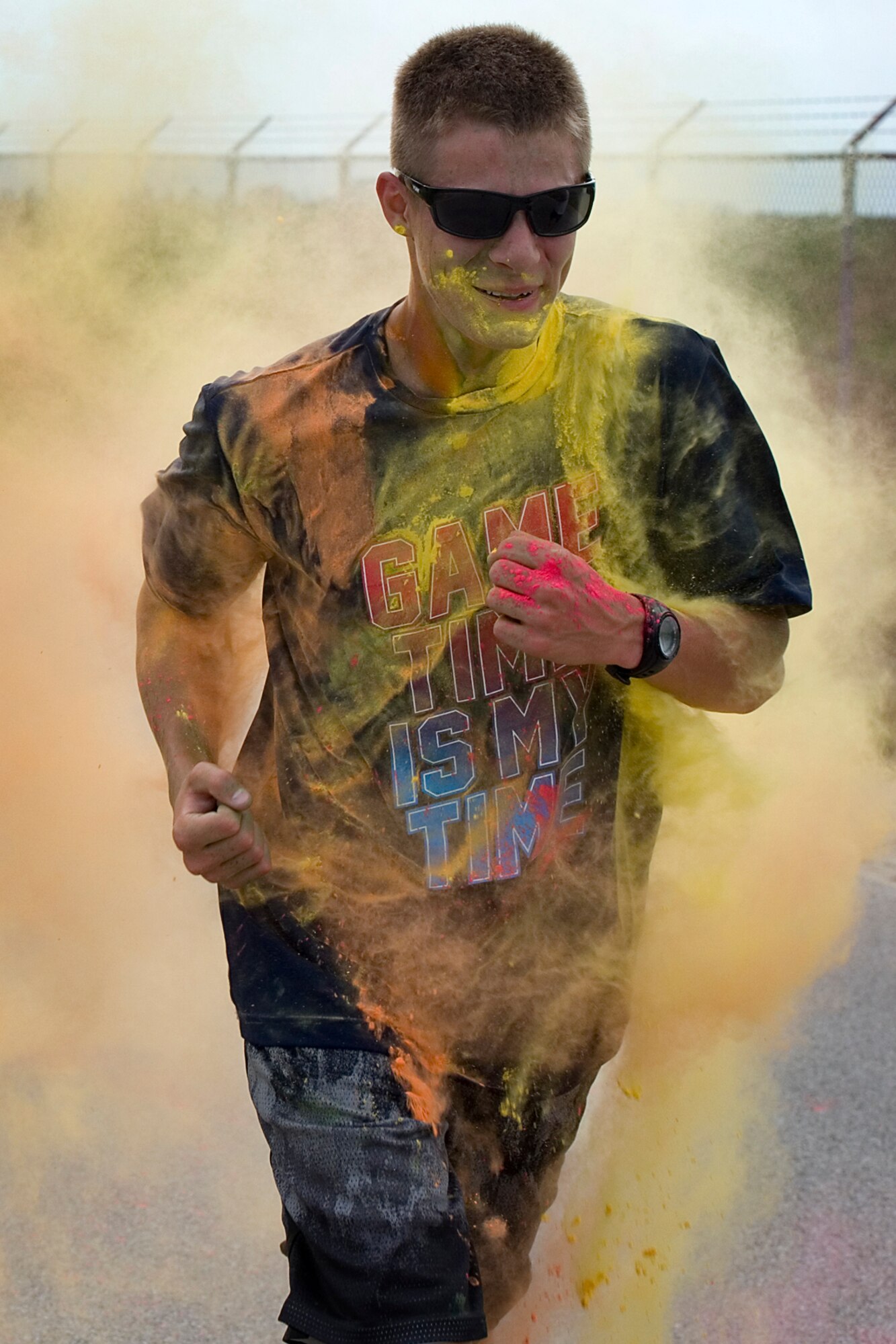 A runner pierces a cloud of color during a 5k color fun run held August 8, 2015 at Grissom Air Reserve Base, Ind. Eighteen runners faced high temperatures and volunteers set on dousing them with bright colored powder. (U.S. Air Force photo/Senior Airman Jami K. Lancette)