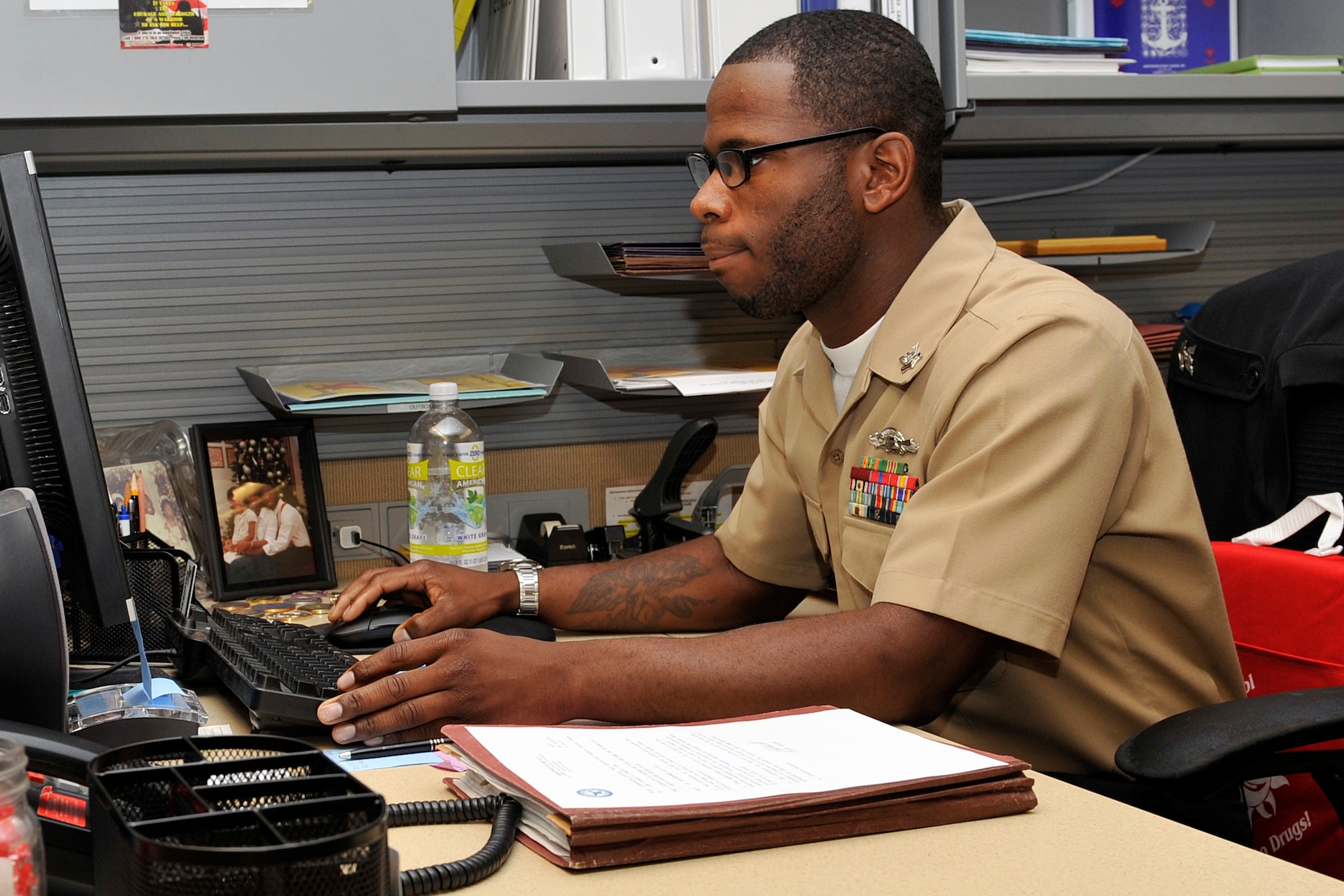 U.S. Navy Petty Officer Second Class Tyrone Ferguson, Naval Operations Support Center – Omaha administrative clerk, downloads some information at his desk July 28. Ferguson is a member of the Omaha Stockmen semi-pro football team. (U.S. Air Force photo by Jeff W. Gates/Released)

