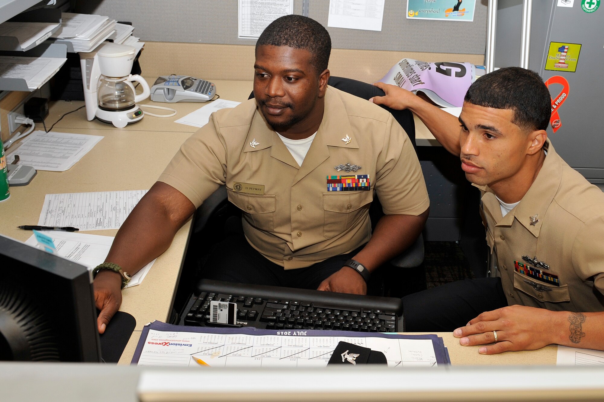 U.S. Navy Petty Officer Deshawn Petway and Petty Officer Ronnie Frost, gather to look at some training records July 28. Petway and Frost are members of the Omaha Stockmen semi-pro football team and work at the Navy Operational Support Center – Omaha, Offutt Air Force Base, Nebraska. (U.S. Air Force photo by Jeff W. Gates/Released)