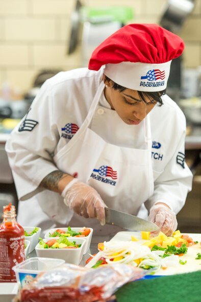Senior Airman Tanise Leitch, 5th Force Support Squadron food services journeyman, prepares a salad during the first Iron Chef Global Strike Challenge competition in the Jimmy Doolittle Center at Minot Air Force Base, N.D., Aug. 10, 2015. The winning team consisted of Staff Sgt. Jeremy Reynolds, 5th FSS missile chef supervisor, Staff Sgt. Ralaun Kidd, 5th FSS food service supervisor, and Leitch. (U.S. Air Force photo/ Airman 1st Class Justin T. Armstrong)