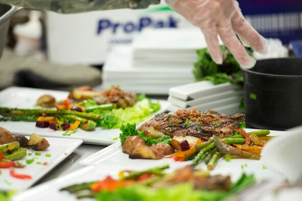 An Airmen from the 5th Force Support Squadron sprinkles green onions on their team’s dish during the first Iron Chef Global Strike Challenge competition in the Jimmy Doolittle Center at Minot Air Force Base, N.D., Aug. 10, 2015. At the start of the challenge, competitors were given a secret ingredient — beets, which had to be incorporated into their dishes. (U.S. Air Force photo/ Airman 1st Class Justin T. Armstrong)
