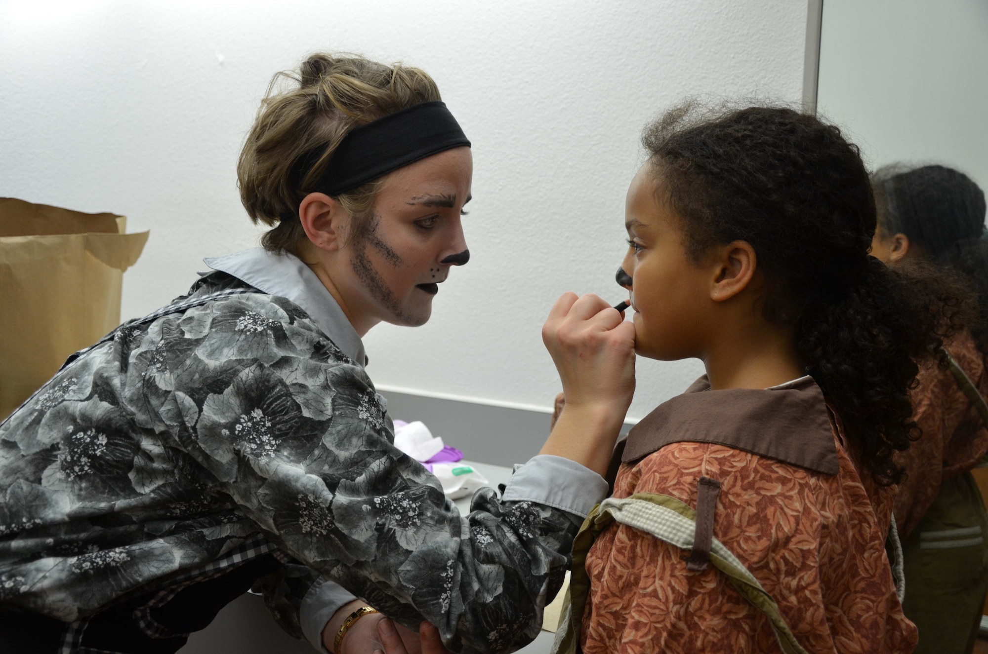 Missoula Children's Theater actor Lindsey Oetken applies stage makeup to Dalelia Jourdain, a member of "The Wolfgang" in the stage production of "Red Riding Hood." Oetken and Jourdain, along with several dozen other young thespians, performed in the Patrick Air Force Base Youth Center's annual performance July 27, 2015.  (U.S. Air Force photo by Susan A. Romano)


