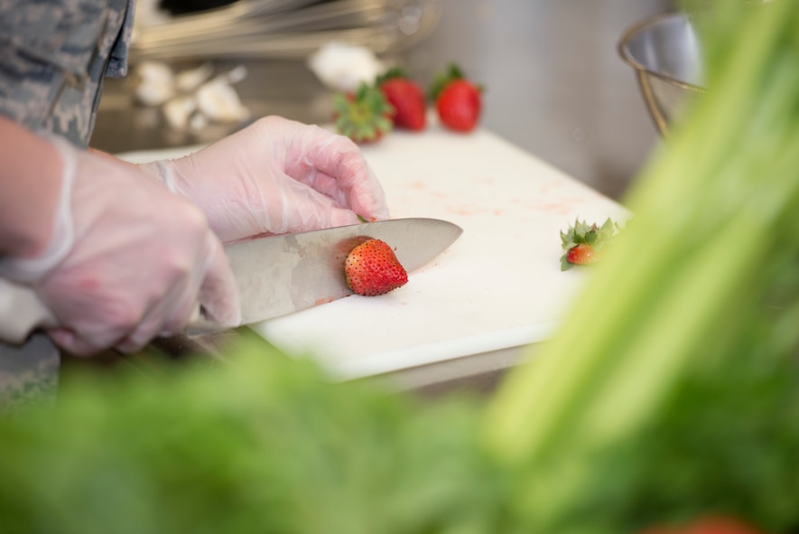 Airman 1st Class Stormie Geiger, 5th Force Support Squadron missile chef, cuts strawberries during the first Iron Chef Global Strike Challenge competition in the Jimmy Doolittle Center at Minot Air Force Base, N.D., Aug. 10, 2015. Three teams of three chefs from 5th FSS had one hour to complete their meals for the judges. (U.S. Air Force photo/ Airman 1st Class Justin T. Armstrong)

