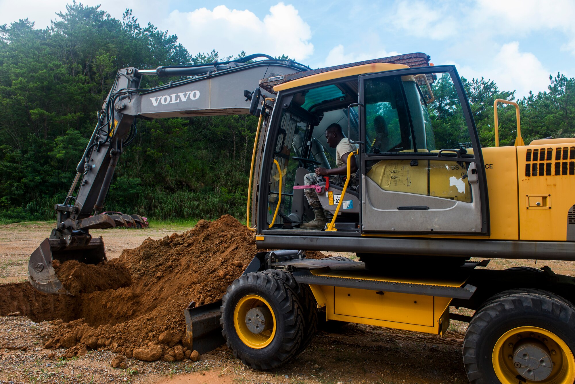 A member of the 18th Civil Enginner Squadrons Heavy Repair Flight (Dirt Boys) digs a 6 foot deep hole for unserviceable munitions and unexploaded ordnance on Kadena Air Base, Japan, Aug 12, 2015. The 18th CES Explosive Ordnance Disposal Flight was completing routine disposal of recovered UXOs found on Kadena AFB. (U.S. Air Force photo by Senior Airman Stephen G. Eigel)