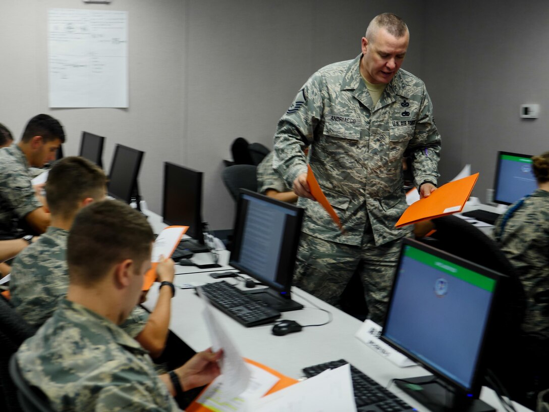 Air Force Master Sgt. Michael Andriacco, Basic Photojournalist Course-Air Force instructor, hands back writing assignments to students from Class 050-15 at the Defense Information School, Fort George G. Meade, Md., Aug. 6, 2015. BPJC-USAF provides instruction in command information, community engagement, media relations, new writing and basic still photography. (DoD photo by Joseph Coslett/Released)