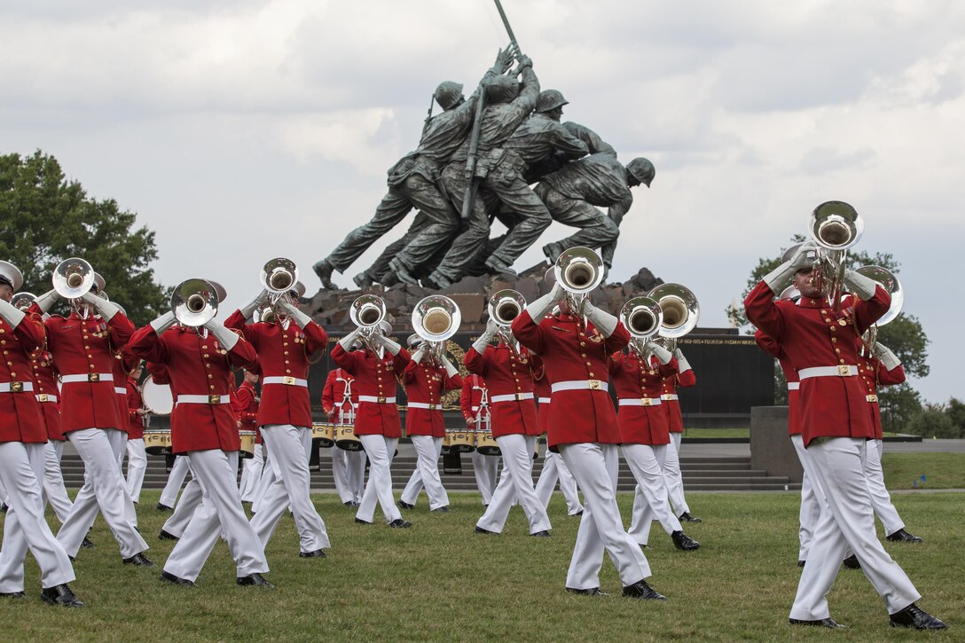 The U.S. Marine Drum and Bugle Corps performs during a sunset parade in front of the Marine Corps War Memorial, Arlington, Va., Aug. 11, 2015. Ms. Hollister K. Petraeus, CFPB Assistant Director, Servicemember Affairs, was the guest of honor for the parade, and Sgt. Maj. Ronald L. Green, 18th Sergeant Major of the Marine Corps, was the hosting official. Since September 1956, marching and musical units from Marine Barracks Washington, D.C., have been paying tribute to those whose “Uncommon Valor was a common virtue” by presenting sunset parades in the shadow of the 32-foot high figures of the United States Marine Corps War Memorial. (U.S. Marine Corps photo by Lance Cpl. Samantha K. Draughon/Released)
