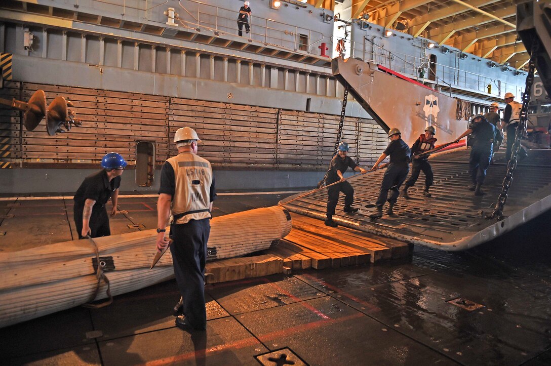 U.S. sailors cover the stern gate of Landing Craft Utility 1666 with a friction mat before loading a utility truck onto the amphibious dock landing ship USS Ashland at Saipan Harbor, Saipan, Aug. 11, 2015 The utility truck will be taken to affected areas for disaster relief efforts in Saipan after Typhoon Soudelor.