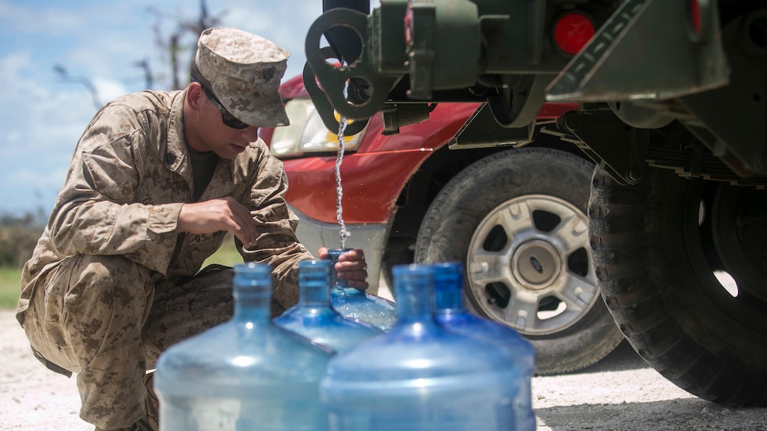 U.S. Marine Sgt. Jeffery Grebbs, with Combat Logistics Battalion 31, 31st Marine Expeditionary Unit, distributes water to local civilians as part of typhoon relief efforts in Saipan, Aug. 11, 2015. The 31st MEU and the ships of the Bonhomme Richard Amphibious Ready Group are assisting the Federal Emergency Management Agency with distributing emergency relief supplies to Saipan after the island was struck by Typhoon Soudelor Aug. 2-3.