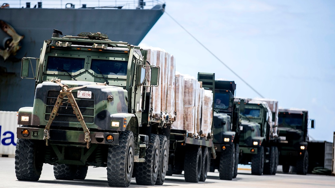 U.S. Marine 7-ton trucks with Combat Logistics Battalion 31, 31st Marine Expeditionary Unit, prepare to distribute water and supplies from the USS Ashland to local civilians as part of typhoon relief efforts in Saipan, Aug. 11, 2015. The 31st MEU and the ships of the Bonhomme Richard Amphibious Ready Group are assisting the Federal Emergency Management Agency with distributing emergency relief supplies to Saipan after the island was struck by Typhoon Soudelor Aug. 2-3.