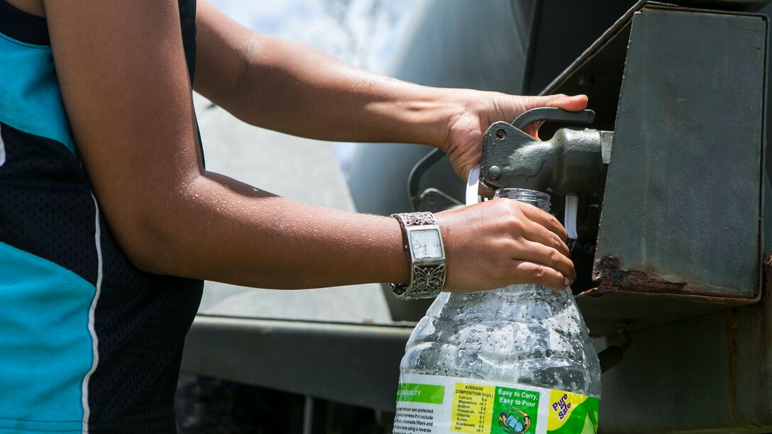 A local boy fills a water jug at a water distribution site set up by U.S. Marines with Combat Logistics Battalion 31, 31st Marine Expeditionary Unit, as part of typhoon relief efforts in Saipan, Aug. 12, 2015. The 31st MEU and the ships of the Bonhomme Richard Amphibious Ready Group are assisting the Federal Emergency Management Agency with distributing emergency relief supplies to Saipan after the island was struck by Typhoon Soudelor Aug. 2-3.