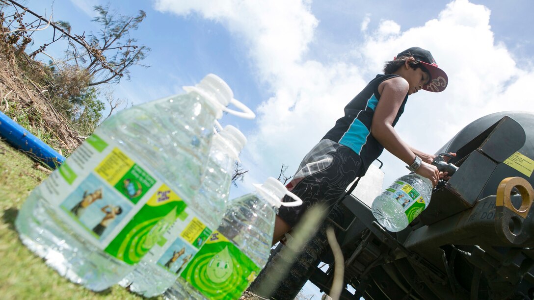 A local boy fills a water jug at a water distribution site set up by U.S. Marines with Combat Logistics Battalion 31, 31st Marine Expeditionary Unit, as part of typhoon relief efforts in Saipan, Aug. 12, 2015. The 31st MEU and the ships of the Bonhomme Richard Amphibious Ready Group are assisting the Federal Emergency Management Agency with distributing emergency relief supplies to Saipan after the island was struck by Typhoon Soudelor Aug. 2-3.