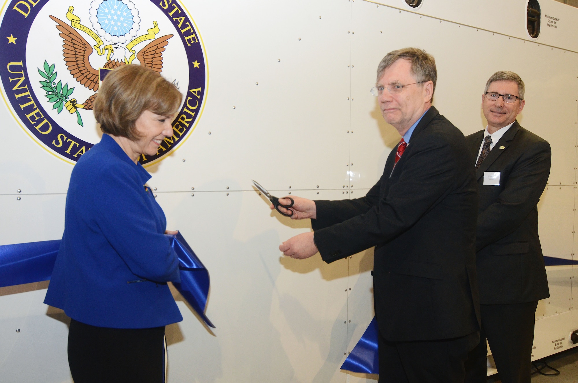 Patrick Kennedy, Under Secretary of Management from the United States Department of State; Barbara Bennett, President and COO of Vulcan, Inc.; and Dr. Tom Sack, President and CEO of MRI Global, perform the ribbon cutting ceremony during the unveiling of the Department of State Containerized Biocontainment System held at Dobbins Air Reserve Base, Ga. Aug 11, 2015. (U.S. Air Force photo/Don Peek)