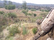 Marines move from their security position in a single file line in preparation to assault their last objective point.