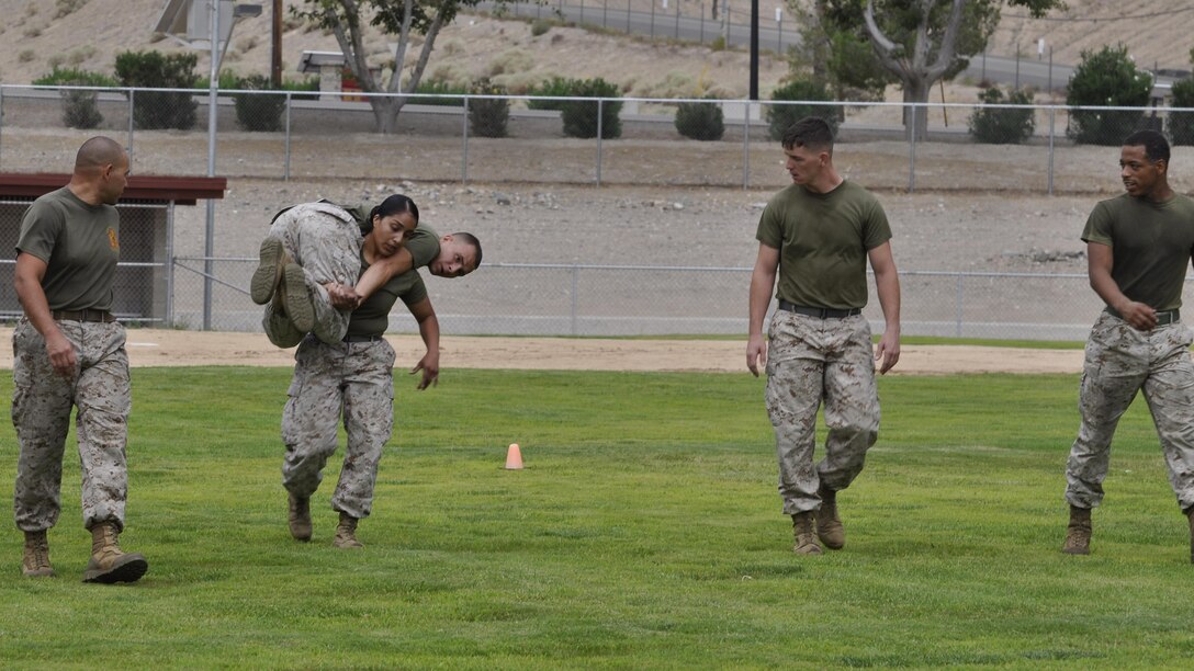Lance Cpl. Cristina Zamora, postal clerk, Sgt. Jonathan Yager, services sergeant, the length of Sorenson Field as part of a HITT competition, while Gunnery Sgt. Antonio Flores, Jr., base gunnery sergeant, Cpl. Michael Browne, supply technician and Lance Cpl. Robert Taylor, communications technician, offer words of encouragement aboard Marine Corps Logistics Base Barstow, Calif., July 30. Lance Cpl. Zamora and Sgt. Justin Mears, retail manager with Marine Corps Community Services, will represent MCLBB at the Ultimate HITT Athlete Competition aboard 29 Palms Air Ground Combat Center in September where they will compete with other Marines from bases Corps-wide. 