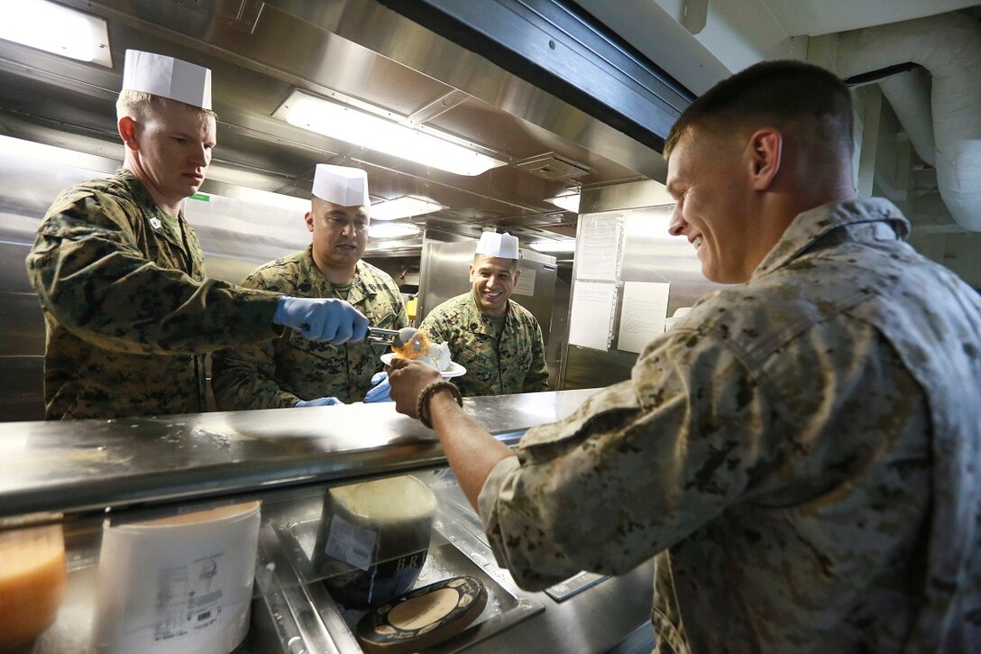 GULF OF ADEN (Aug. 7, 2015) U.S. Marines Gunnery Sgt. Karl Warnstedt, Michael Ramirez, and Eddy Arce, left to right, serve ice cream to Sgt. Dakota Newsome during an ice cream social aboard the amphibious transport dock ship USS Anchorage (LPD 23). All are members of Battalion Landing Team 3rd Battalion, 1st Marine Regiment, 15th Marine Expeditionary Unit.  The 15th MEU is embarked on the Essex Amphibious Ready Group and deployed to maintain regional security in the U.S. 5th Fleet area of operations. (U.S. Marine Corps photo by Sgt. Steve H. Lopez/ Released)