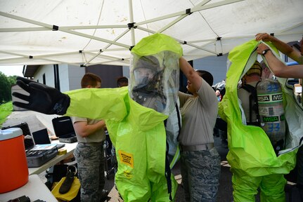 In this photo, Senior Airman Timothy Burnett, 51st Medical Group Aerospace Medicine Squadron bioenvironmental engineering journeyman, and Airman 1st Class Benjamin Thompson, 51st Civil Engineer Squadron emergency management apprentice, are assisted into their level A chemical, biological, radiological and nuclear protection suits as part of an exercise at Osan Air Base, Republic of Korea, Aug 4, 2015.  The scenario is part of a week-long series of intense, integrated base emergency response capability training exercises for initial and follow-on responders. 