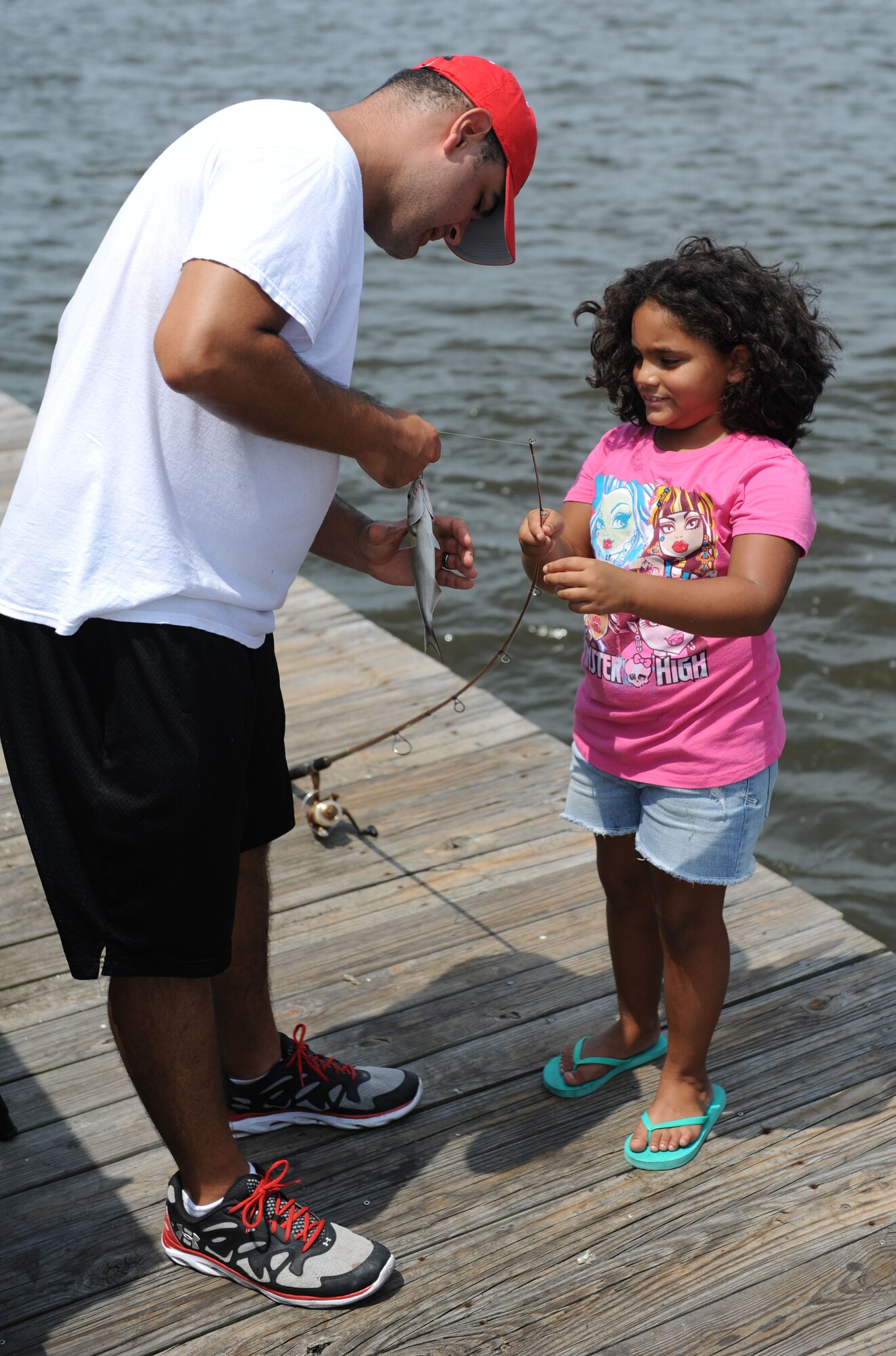 Army Staff Sgt. Jose Ortiz, 81st Medical Support Squadron, assists his daughter, Jianna, with unhooking a fish during the Kid’s Fishing Rodeo Aug. 8, 2015, at the marina, Keesler Air Force Base, Miss. The event was hosted by the outdoor recreation center and Gulfport Elks Lodge. (U.S. Air Force photo by Kemberly Groue)