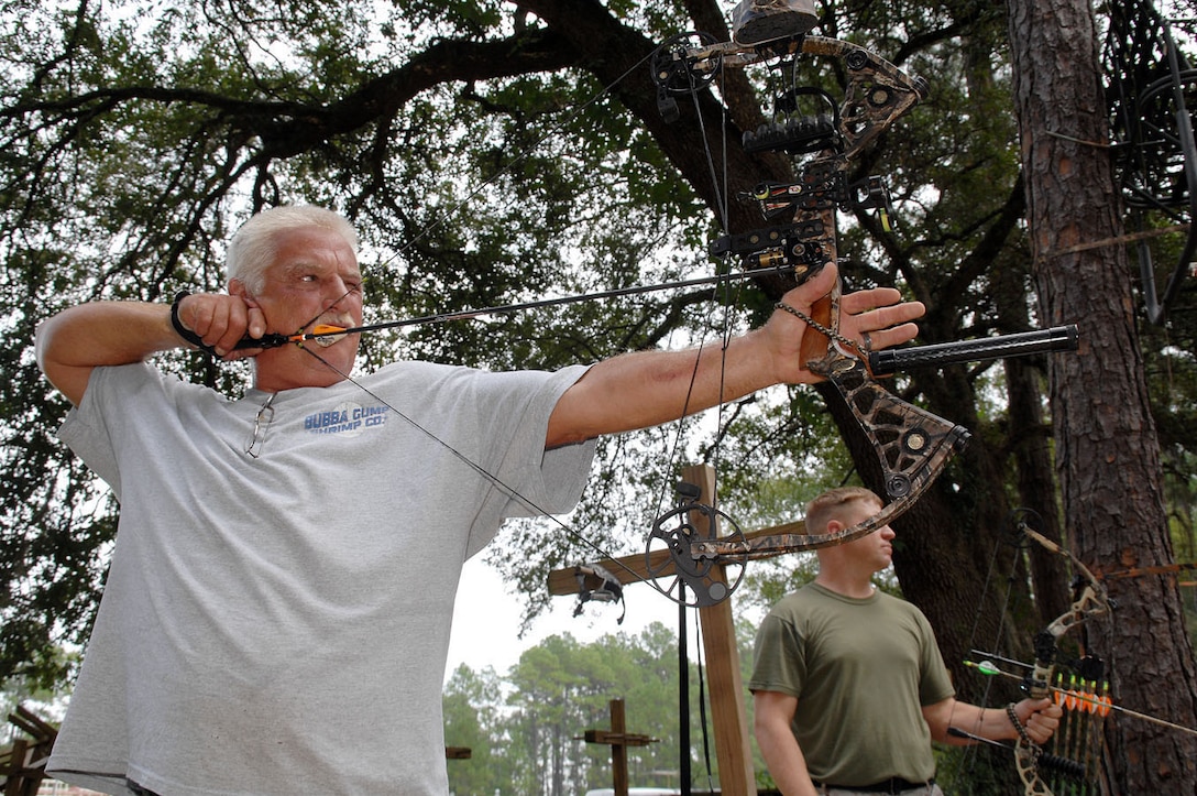 Chuck Peay, woodworker, Defense Logistics Agency Distribution Albany, Ga., practices with his bow at Marine Corps Logistics Base Albany's Archery Range, Aug. 10.  Gunnery Sgt. Steven Ramus, assault amphibious vehicle mechanic, Maintenance Management Center, Marine Corps Logistics Command, verifies Peay’s shot pattern. 