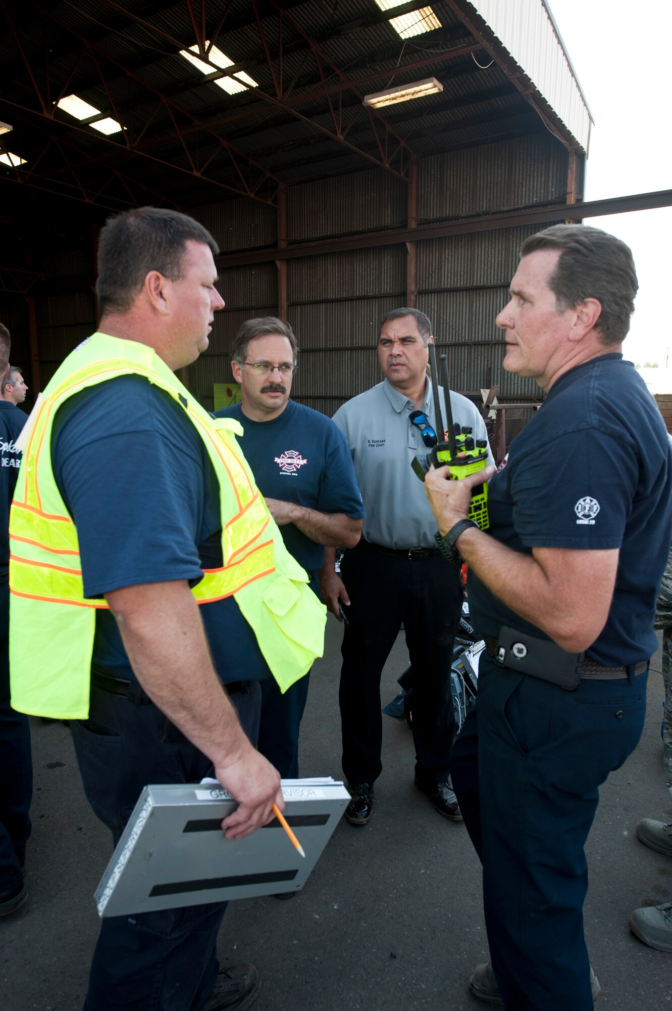 Kimo Kuheana, 92nd Civil Engineer Squadron fire chief speaks with civilian counterparts Aug. 12, 2015, at Pacific Steal and Recycling in Spokane Wash.  The cause of the chemical leak was an unmarked 55-gallon drum picked up for recycling and put into the recycling center’s crushing machine, releasing a yellow-green gas that caused respiratory distress and hospitalization for those present. (U.S. Air Force photo/Airman Sean Campbell)