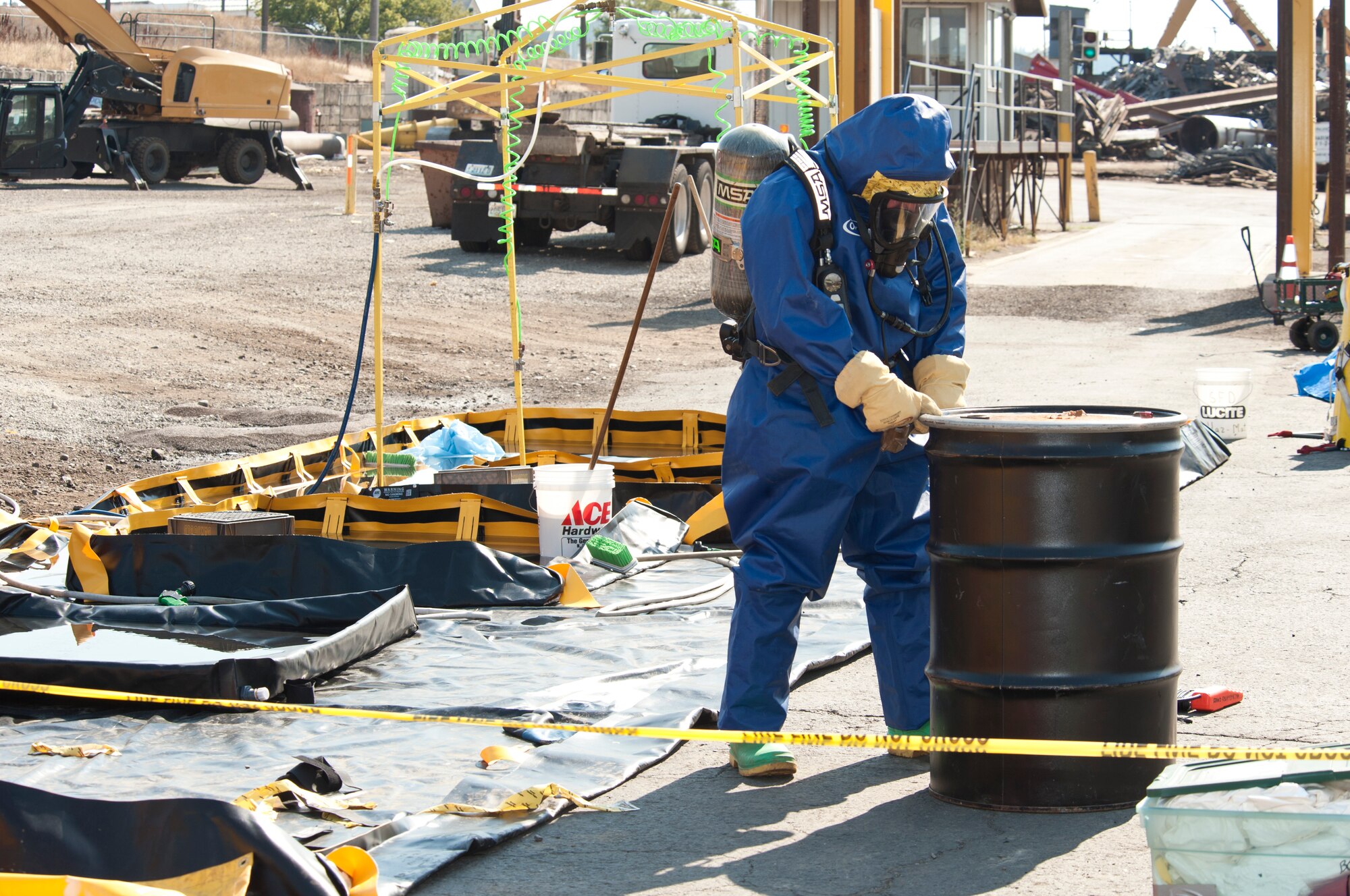 Senior Airman Nicholas Bouselli, 92nd Civil Engineer Squadron emergency management journeyman, approaches a metal drum containing the clothes of those directly exposed to a chlorine gas leak Aug. 12, 2015, at Pacific Steal and Recycling in Spokane Wash.  More than 25 people felt the effects of the chemical leak and have since been treated by medical responders. (U.S. Air Force photo/Airman Sean Campbell)