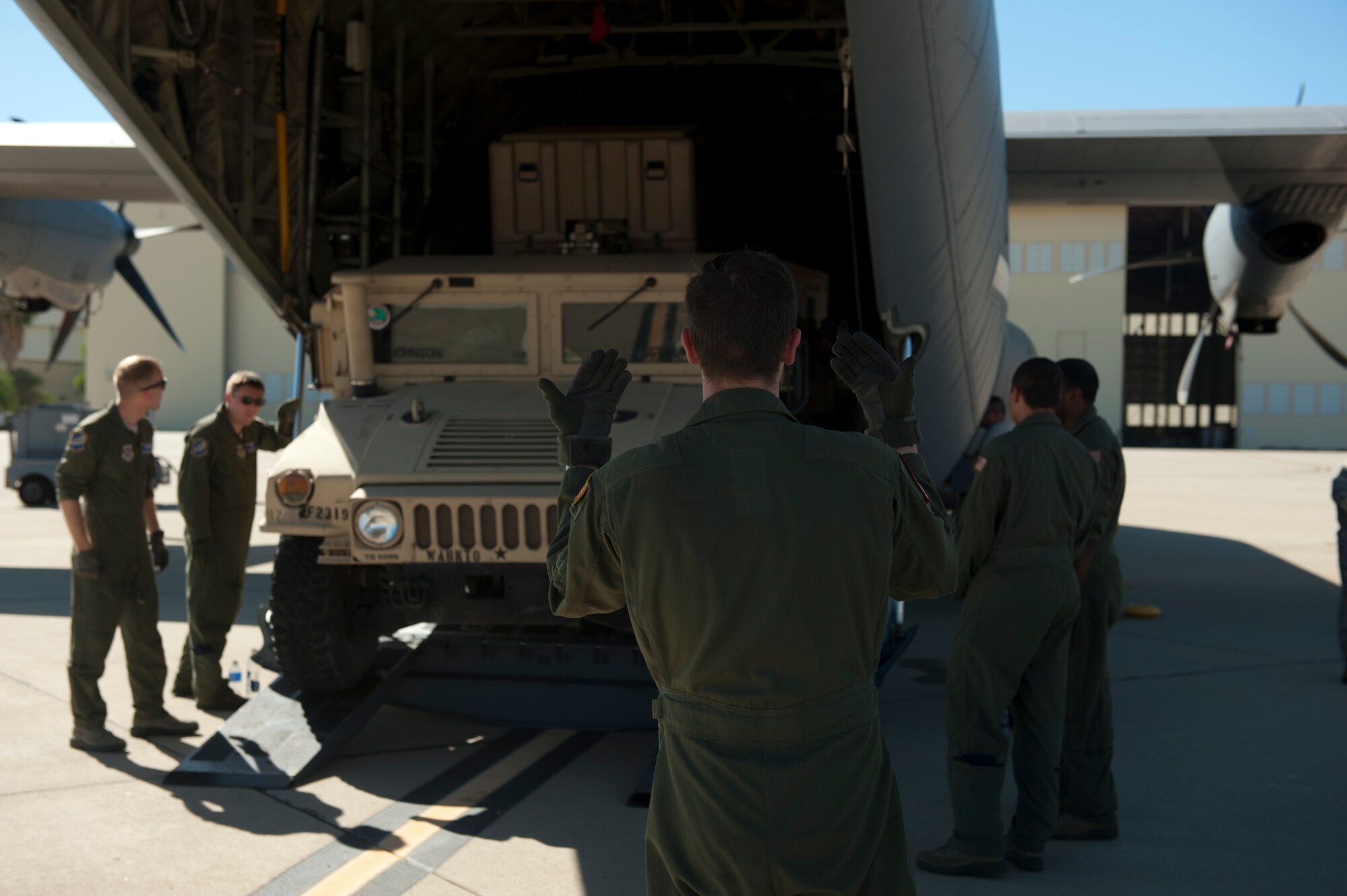 Senior Airman William Rush, a 41st Airlift Squadron loadmaster, marshals a Humvee into a C-130J Aug. 4, 2015, at March Reserve Air Force Base, Calif. The 41st AS was taking part in Operation Dragon Spear, a joint operations access exercise where their mission was to support large formation operations by providing C-130 Combat Airlift with Army assets. (U.S. Air Force photo by Senior Airman Scott Poe)