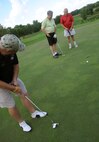 Tech. Sgt. Chad Knoblauch of the 69th Maintenance Squadron on Grand Forks Air Force Base, putts while teammates watch at the biannual Military Affairs Committee golf tournament in Grand Forks, North Dakota, Aug. 10, 2015. Nineteen teams made up of golfers from on base and the local community played in the tournament. (U.S. Air Force photo by Senior Airman Desiree Economides/Released)