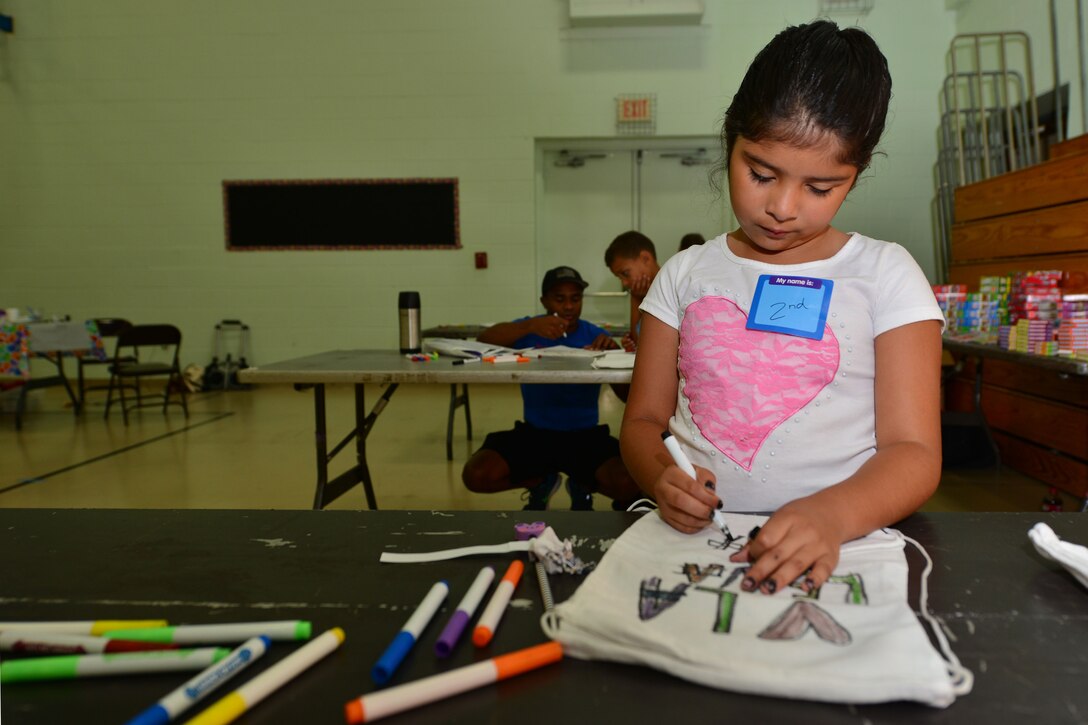 Elena Sergio draws on a backpack during the Fort Eustis back-to-school block party at the Middle School and Teen Center at Fort Eustis, Va., Aug. 11, 2015. The party provided military parents an opportunity to network and learn about school-aged programs before their children begin the upcoming school year. (U.S. Air Force photo by Staff Sgt. Natasha Stannard/Released)