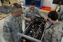 Chief Master Sgt. Gerardo Tapia, Air Education and Training Command command chief, receives instruction from Staff Sgt. Dustin Rysavy-Hollis, 47th Flying Training Wing Maintenance Directorate Egress Shop egress technician, and Staff Sgt. Tara Swanson, 47th Flying Training Wing Maintenance Directorate Egress Shop egress technician, on how an ejection seat works on Laughlin Air Force Base, August 7, 2015. Egress handles the fixing of the lap belts and the replacing of the explosive charges that blast the canopy and launch the pilot's flight seat. (U.S. Air Force photo by Airman 1st Class Brandon May)(Released)