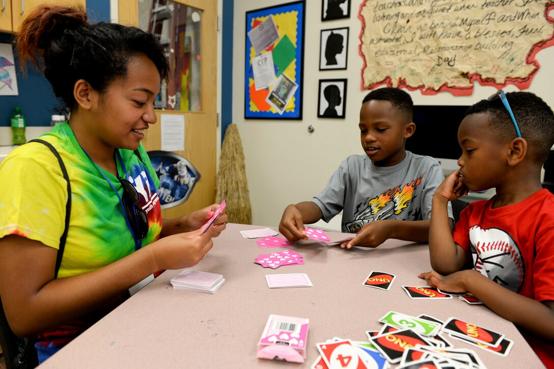 Jasmeen Parker, Langley Youth Center volunteer plays a card game with two boys at the Langley Youth Program at Langley Air Force Base, Va., July 24, 2015. The staff is comprised of volunteers and government employees who participate in activities with the children. (U.S. Air Force photo by Airman 1st Class Derek Seifert/Released) 