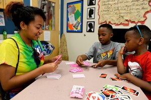 Jasmeen Parker, Langley Youth Center volunteer plays a card game with two boys at the Langley Youth Program at Langley Air Force Base, Va., July 24, 2015. The staff is comprised of volunteers and government employees who participate in activities with the children. (U.S. Air Force photo by Airman 1st Class Derek Seifert/Released) 