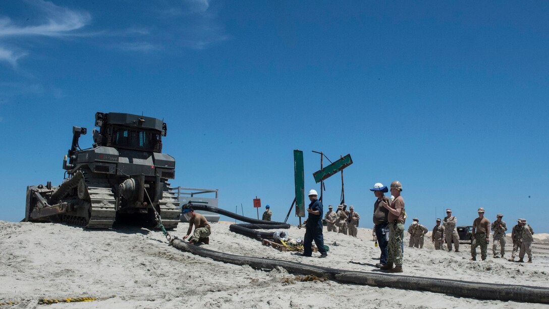 Marines with Bulk Fuel Company, 1st Marine Logistics Group, team up with sailors from Amphibious Construction Battalion 1 to perform a beach unloading exercise using the Beach Termination Unit, in Coronado, California, Aug. 1-4, 2015. Approximately 30 Marines with Bulk Fuel Company, 7th Engineer Support Battalion, 1st Marine Logistics Group, teamed up with sailors from Amphibious Construction Battalion 1 to conduct a beach unloading exercise. What made the training unique was the use of the BTU, which allows Marines to transfer fuel from a ship out in the ocean to Marines on land.