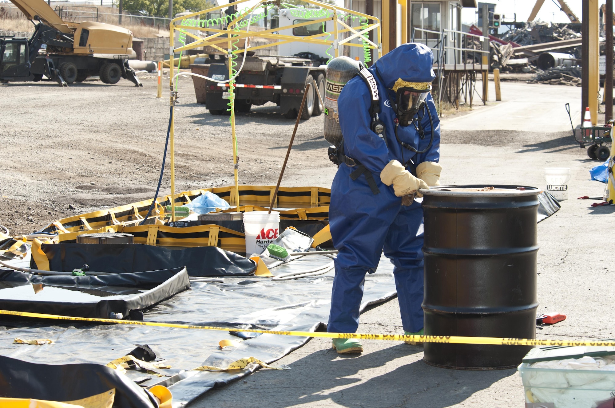 Senior Airman Nicholas Bouselli, a 92nd Civil Engineer Squadron emergency management journeyman, approaches a metal drum containing the clothes of those directly exposed to a chlorine gas leak Aug. 12, 2015, at Pacific Steal and Recycling in Spokane, Wash. More than 25 people felt the effects of the chemical leak and have since been treated by medical responders. (U.S. Air Force photo/Airman Sean Campbell)