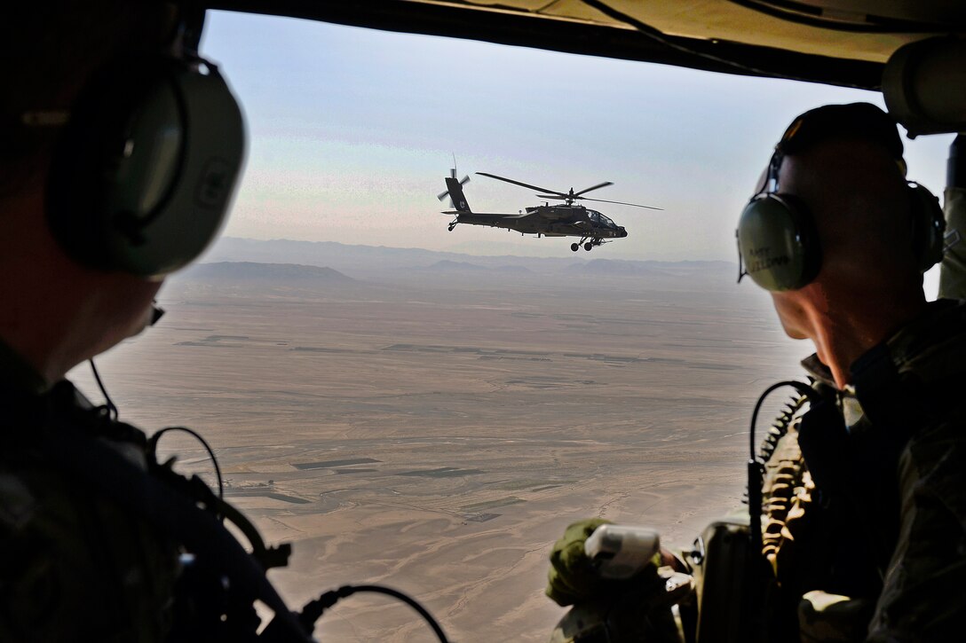 A U.S. Army AH-64 Apache helicopter provides security as Afghan Army Brig. Gen. Dawood Shah Wafadar, commander of the 205th Corps, and U.S. Army Brig. Gen. Paul Bontrager, commander of  Train, Advise, Assist Command South, fly inside a U.S. Army UH-60 Black Hawk helicopter during an aerial battlefield familiarization flight over southern Afghanistan, Aug. 4, 2015.
