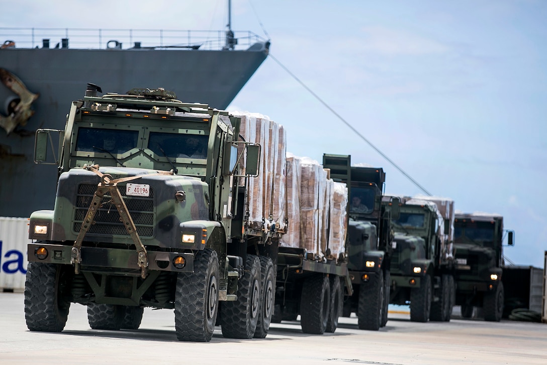 U.S. Marine trucks transport water and supplies from the USS Ashland to civilians as part of typhoon relief efforts in Saipan, Aug. 11, 2015.
