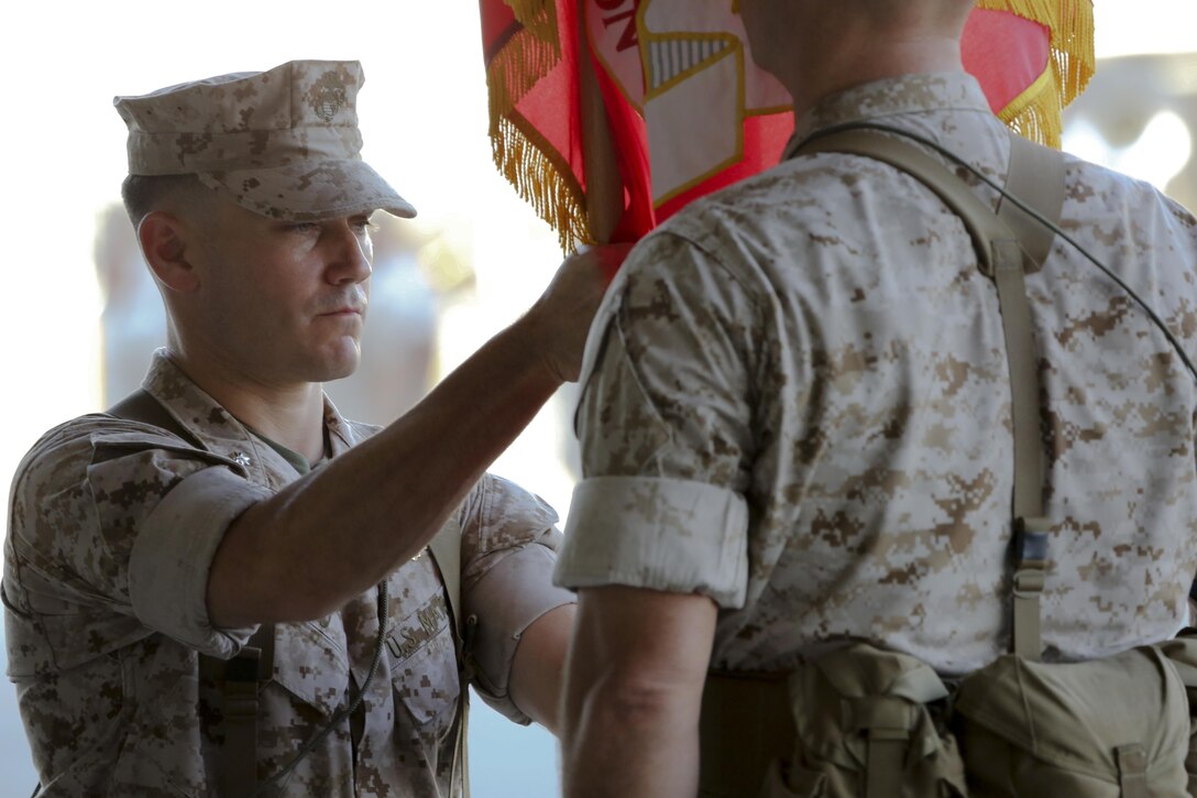 Incoming Marine Fighter Attack Squadron 121 commanding officer, Lt. Col. James Bardo, recieves the squadron colors from outgoing commanding officer, Lt. Col. Steve Gillette, during the squadron's change of command ceremony aboard Marine Corps Air Station Yuma, Arizona, Friday, Aug. 14, 2015. The passing of the colors is the ceremony's most solemn moment, signifying the physical transfer of command from one Marine to the other.