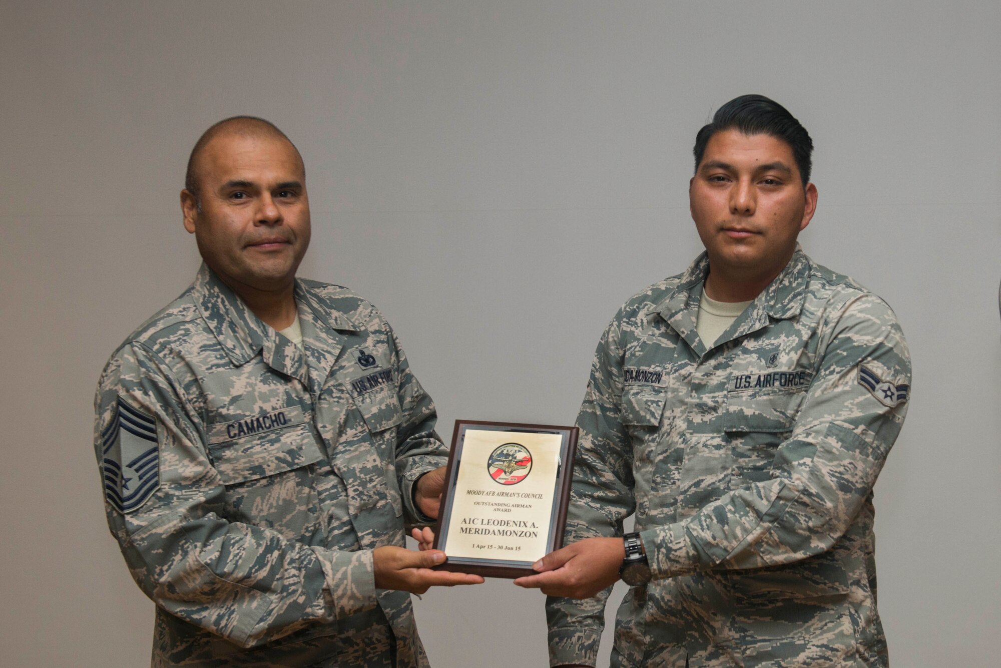 U.S. Air Force Chief Master Sgt. Manuel Camacho (left), 23d Mission Support Group, presents the quarterly Airmen Committed to Excellence Outstanding Airman Award to Airman 1st Class Leodenix Merida-Monzon, 23d Aerospace Medicine Squadron bioenvironmental specialist, during an ACE general membership meeting Aug. 14, 2015, at Moody Air Force Base, Ga. Merida-Monzon received the award for his volunteer work for the organization. (U.S. Air Force photo by Airman 1st Class Dillian Bamman/Released)