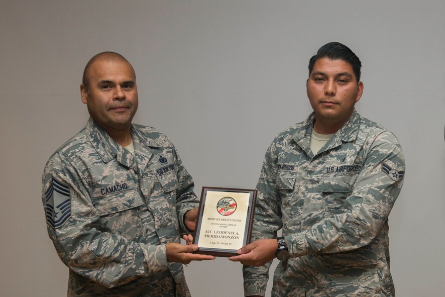 U.S. Air Force Chief Master Sgt. Manuel Camacho (left), 23d Mission Support Group, presents the quarterly Airmen Committed to Excellence Outstanding Airman Award to Airman 1st Class Leodenix Merida-Monzon, 23d Aerospace Medicine Squadron bioenvironmental specialist, during an ACE general membership meeting Aug. 14, 2015, at Moody Air Force Base, Ga. Merida-Monzon received the award for his volunteer work for the organization. (U.S. Air Force photo by Airman 1st Class Dillian Bamman/Released)