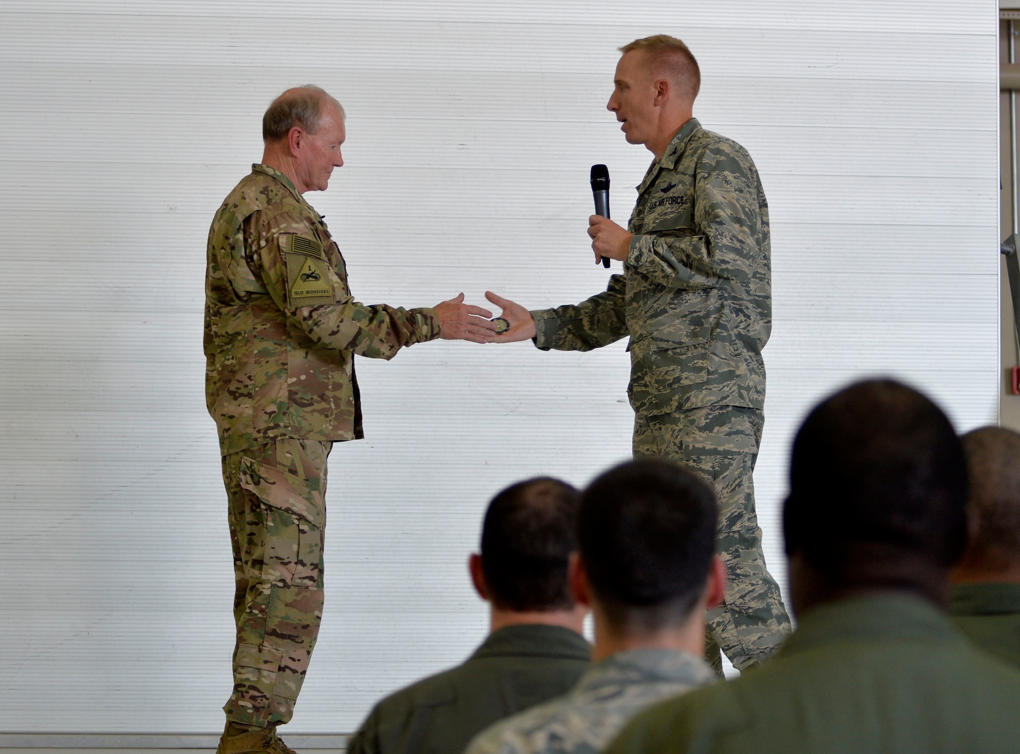 Col. Case Cunningham, 432nd Wing/432nd Air Expeditionary Wing Public Affairs presents a coin to Army Gen. Martin E. Dempsey, Chairman of the Joint Chiefs of Staff speaks after an all-call on Aug. 12, 2015, at Creech Air Force Base, Nevada. During his visit to Creech AFB, Dempsey and his wife Deanie toured the base to ask the Creech Airmen questions. (U.S. Air Force photo by Airman 1st Class Christian Clausen/Released)