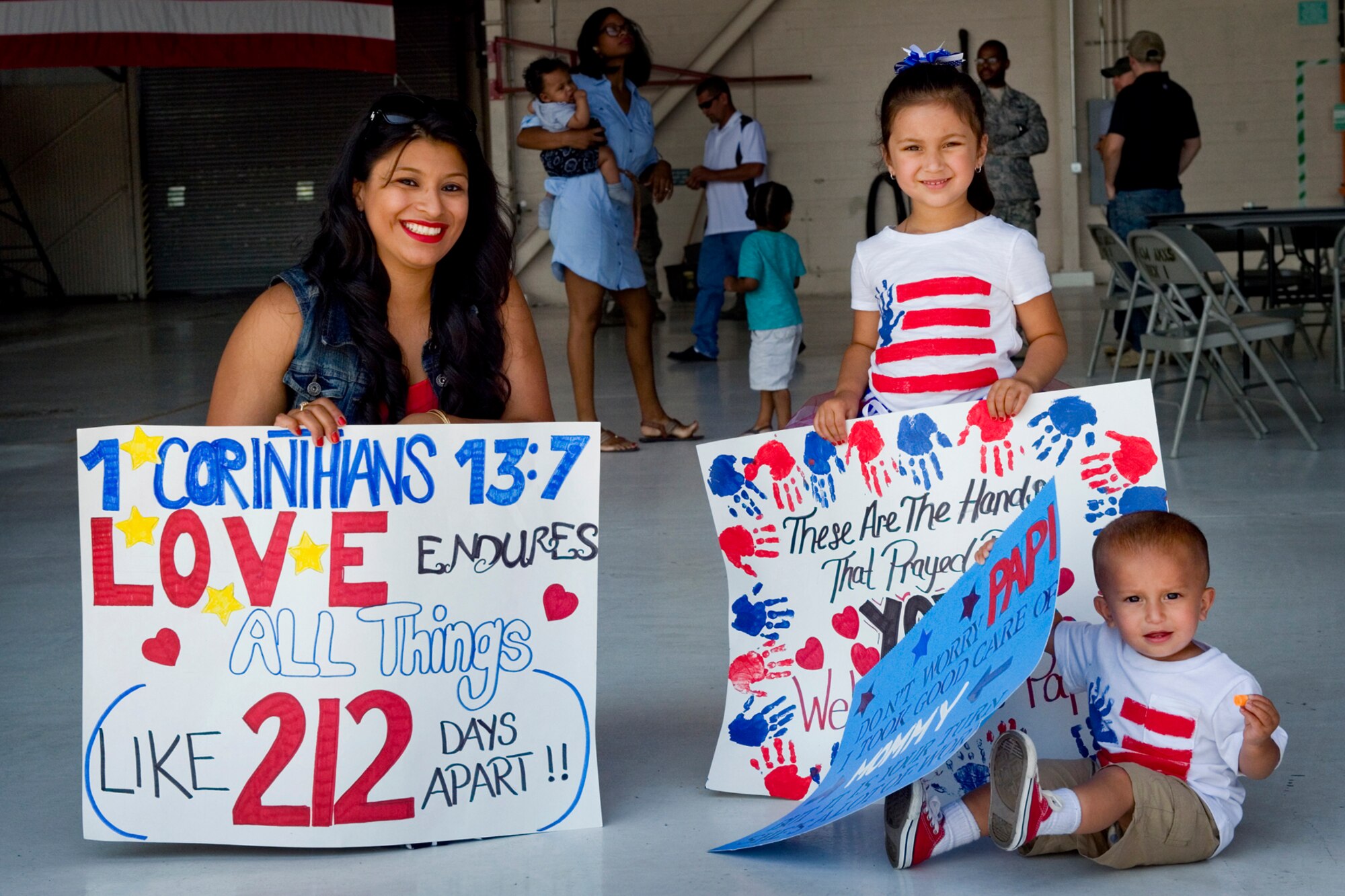 Guadalupe Poremba, wife of Staff Sgt. Timothy Poremba, 434th Security Forces Squadron fire team member, and their children, Gabriela and Alexander, hold signs to greet returning Airmen at Grissom Air Reserve Base, Ind., August 8, 2015. Families and friends gathered to welcome 14 defenders home from a 180-day deployment to Southwest Asia. (U.S. Air Force photo/Tech. Sgt. Benjamin Mota)