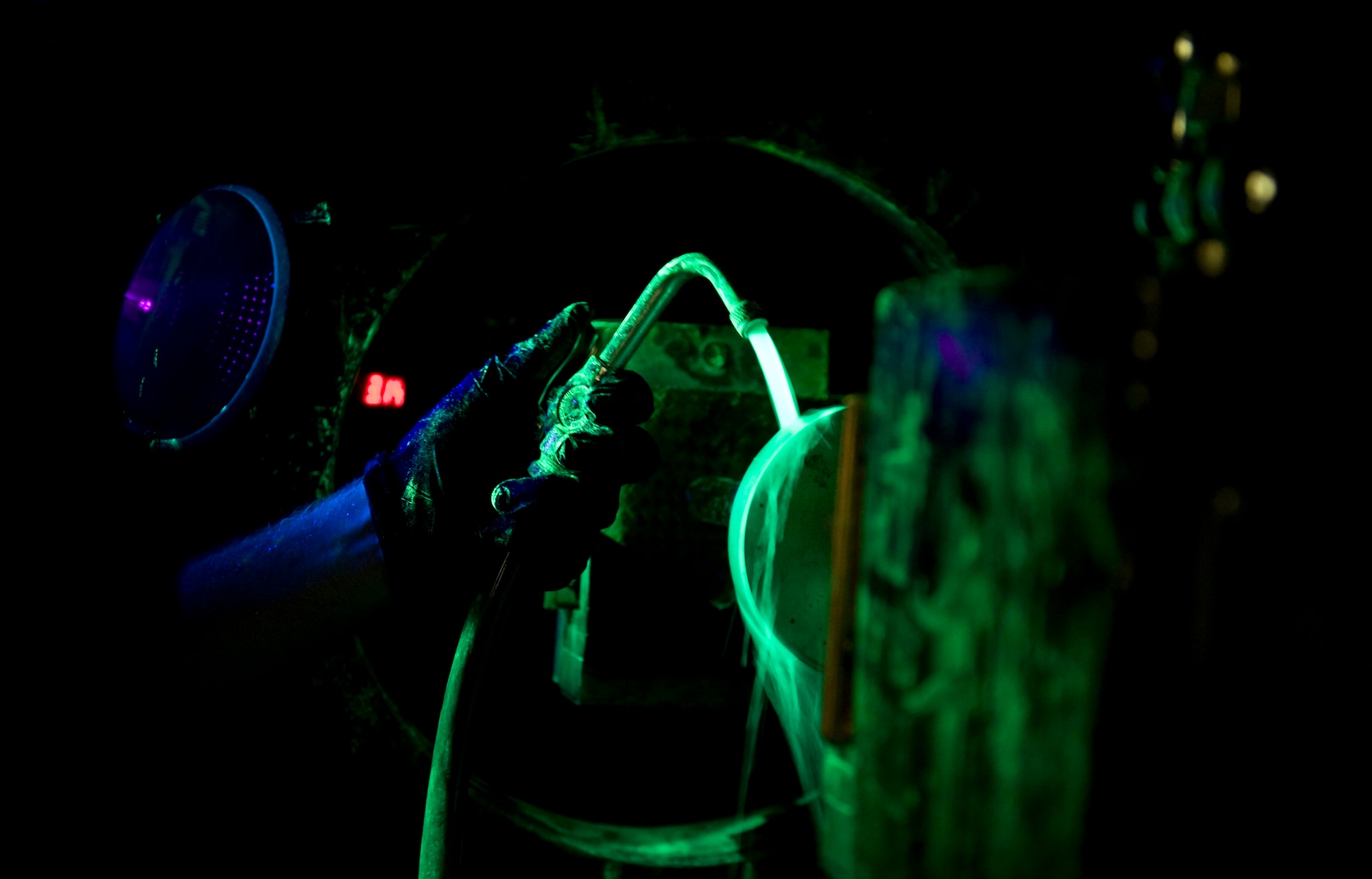 Joey Mabrey, a contractor with the 57th Maintanence Group, performs a fluorescent magnetic particle inspection at the Nondestructive Inspection Laboratory on Nellis Air Force Base, Nev., Aug. 11. Magnetic particle inspections cause the abnormalities, such as cracks on aircraft parts, to be visible. (U.S. Air Force photo by Airman 1st Class Rachel Loftis)