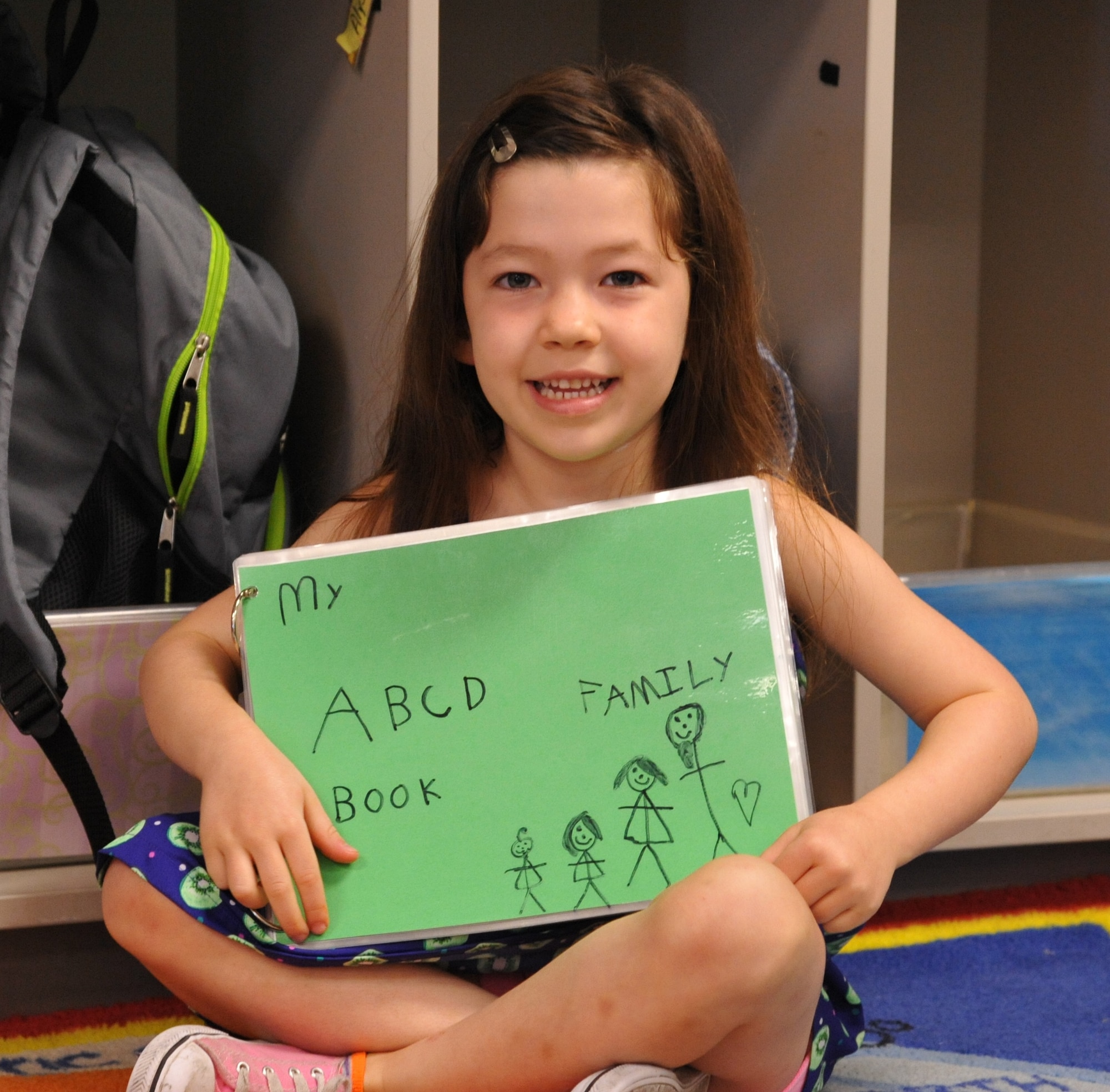 Olivia Russi, a student in room A-14 at Wright Field North Child Development Center, proudly displays the book she wrote and illustrated.  (Air Force photo by Gina Marie Giardina / Released)