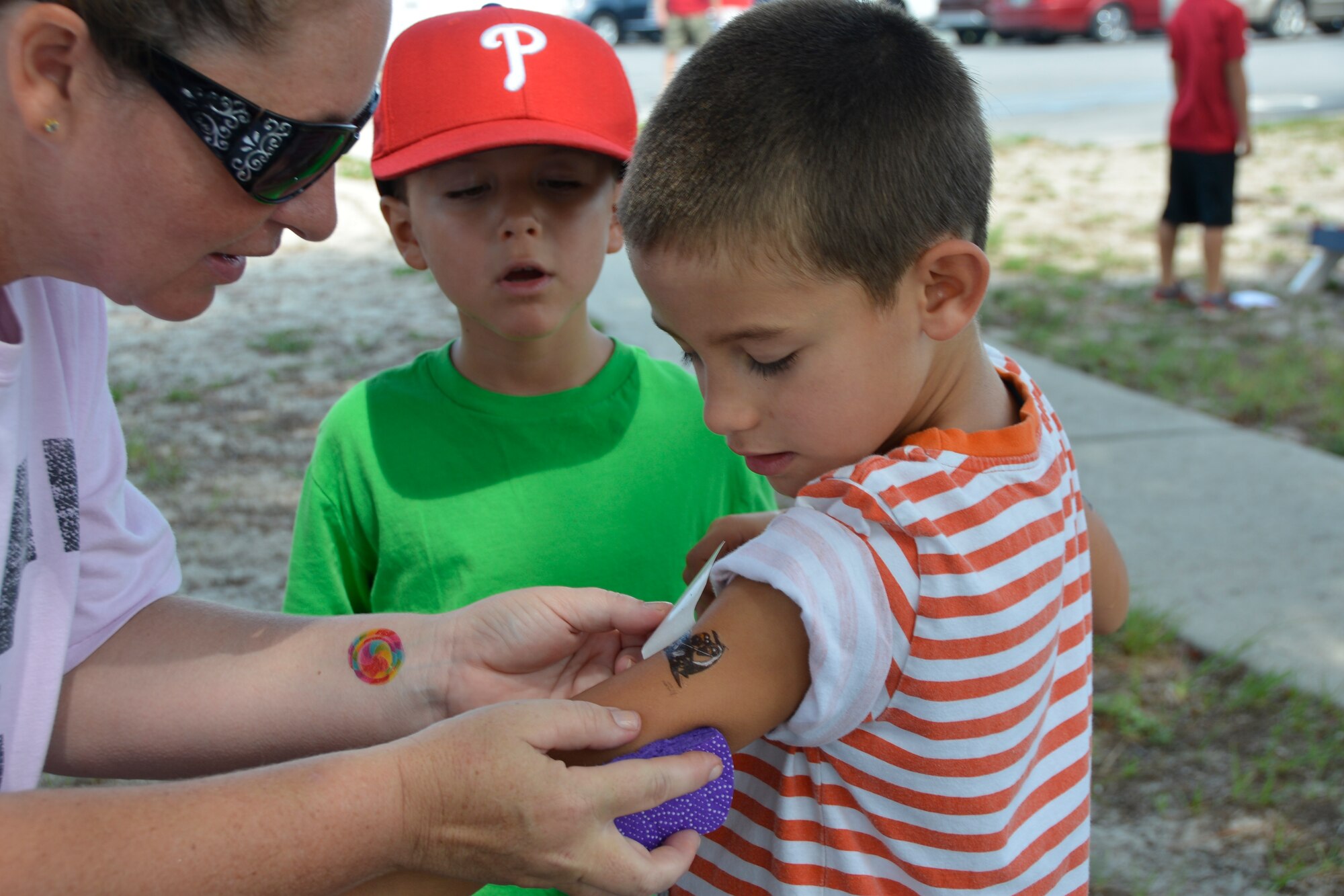 Senior Master Lorene Kitzmiller, 1st Air Force (Air Forces Northern) 1st Sergeant, unveils a temporary tattoo for one of the young visitors during the 1st Air Force (Air Forces Northern) “Family Day 2015” Aug. 7 at Bonita Bay. The day focused on taking care of the organization’s families and featured a variety of activities that included food and sport competitions, a waterslide and plenty to eat and drink. (Air Force Photo Released/Mary McHale)