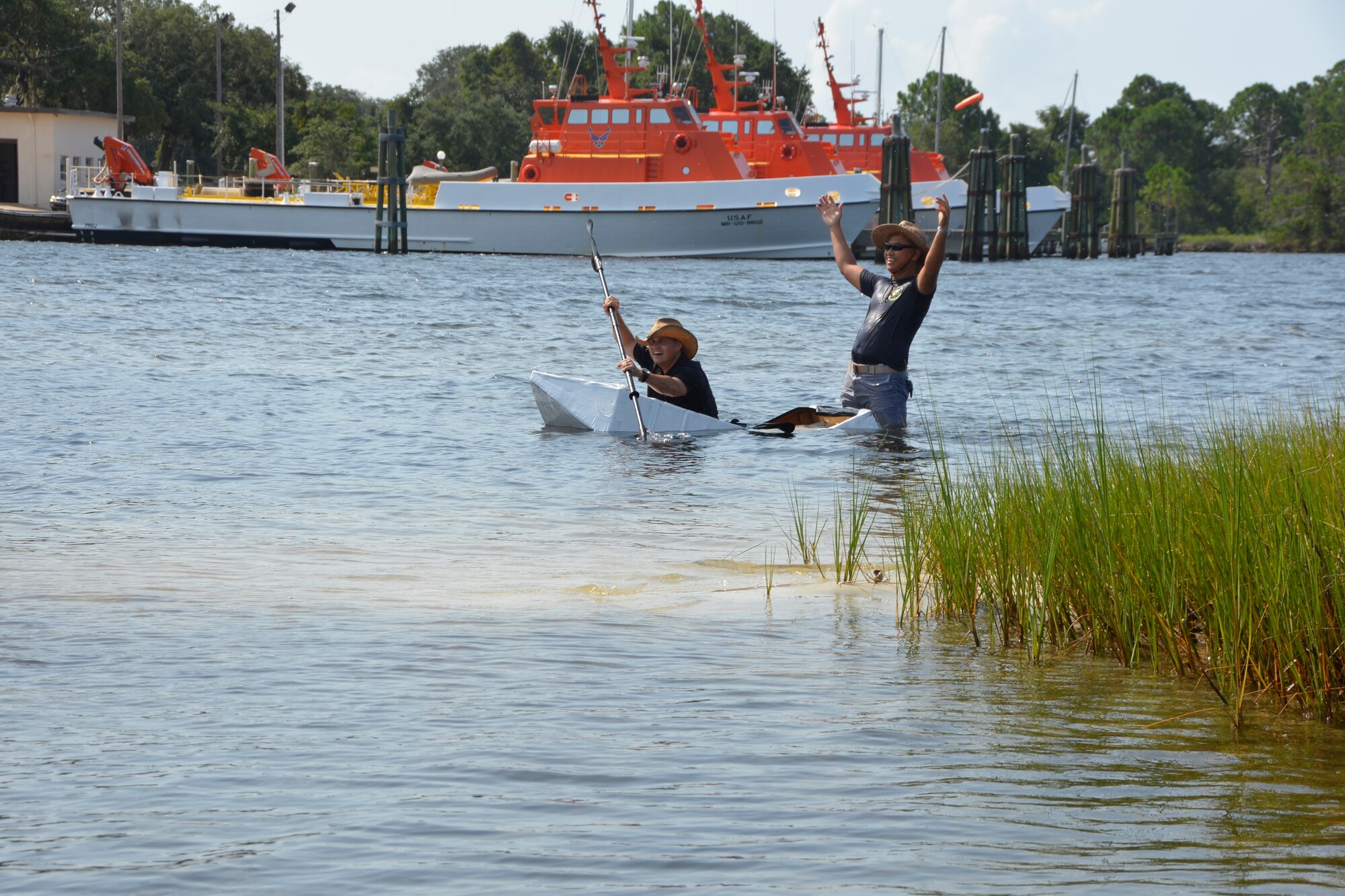 During the 1st AF (AFNORTH) “Family Day 2015” at Bonita Bay Aug. 7, Capt. Robin DeGuzman, (standing), 101st Air Communications Squadron, reacts to the cardboard boat end-of-race-race result after their vessel, piloted by Master Sgt. Brad Weekley, became a bit waterlogged. The race kicked off the day which focused on taking care of the organization’s families and featured a variety of activities that included food and sport competitions, a waterslide and plenty to eat and drink. (Air Force Photo Released/Mary McHale)