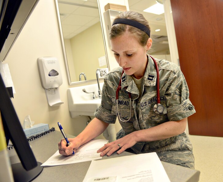 Family physician Capt. Erica Conrad, with the 72nd Medical Operations Squadron, fills out a prescription for a patient for a breast pump. Tricare now covers the cost of breast pumps and breast pump supplies, after a birth event (birth or adoption). If one has already paid for a pump, a claim may be filed, along with a prescription from a Tricare-authorized provider along with an itemized receipt.  (Air Force photo by Kelly White/Released)

