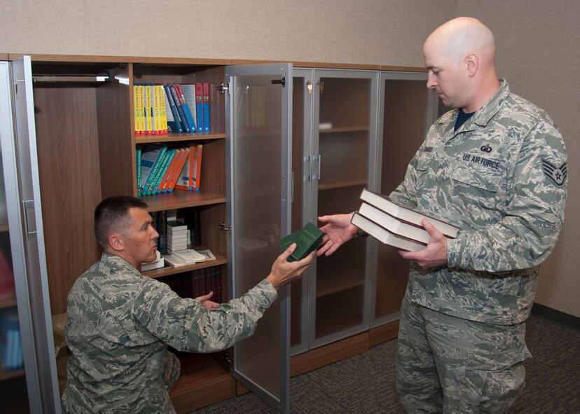 Chaplain (Capt.) Quentin Genke, 436th Airlift Wing chaplain, hands religious text to Staff Sgt. Darick Alexander, 436th Airlift Wing chaplain assistant, August 7, 2015, at Chapel One on Dover Air Force Base, Del. As a chaplain, Chaplain Genke is responsible for religious accommodations such as gathering religious texts or information on religious services within the community. (U.S. Air Force photo/Senior Airman Jared Duhon)