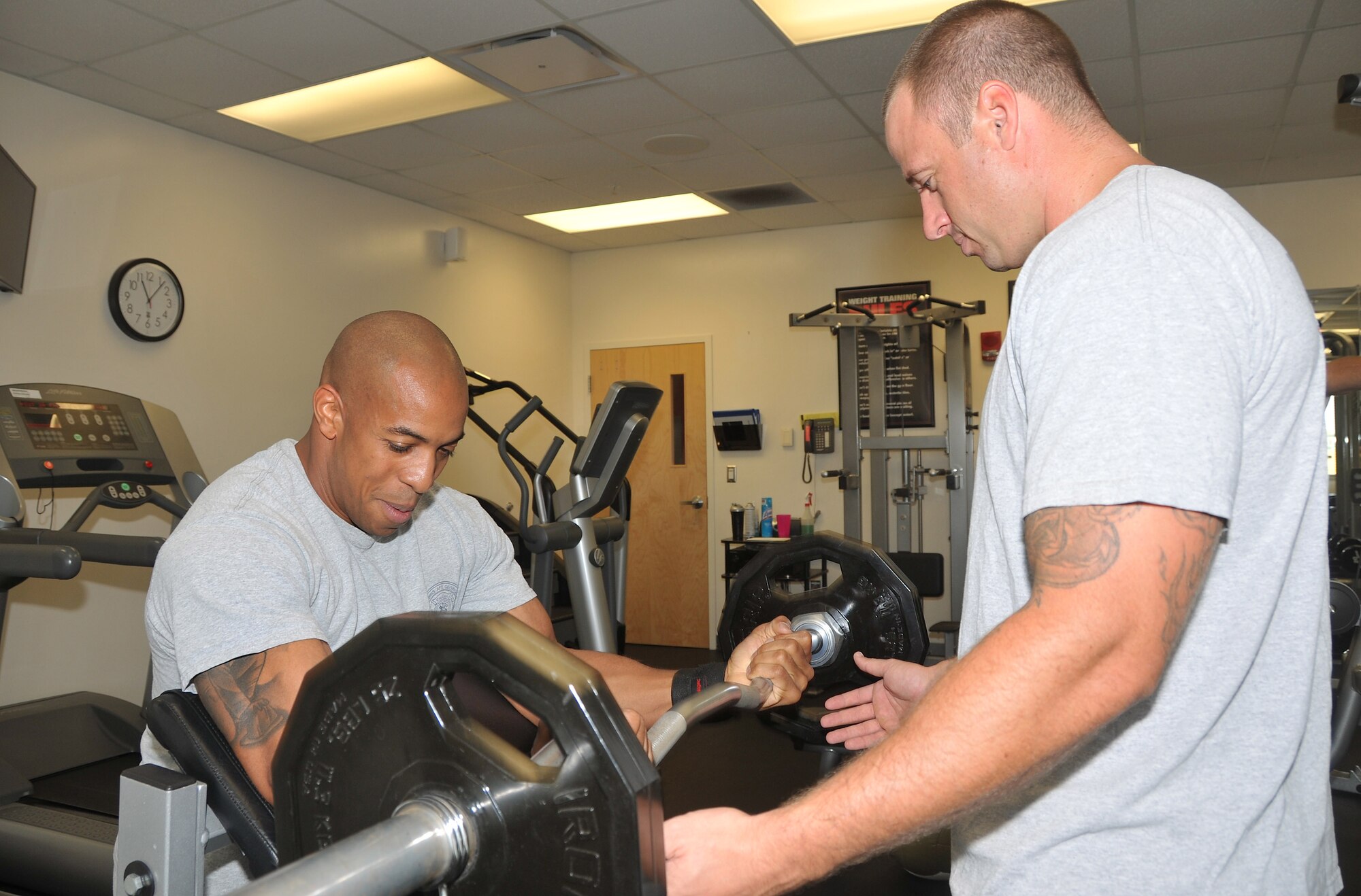 Andrew Shutes (seated), and Nick Hamilton, both Robins Air Force Base firefighters show off their weekly work out routine doing bicep curls and dumbbell shoulder presses. (U.S. Air Force photo by Misuzu Allen)